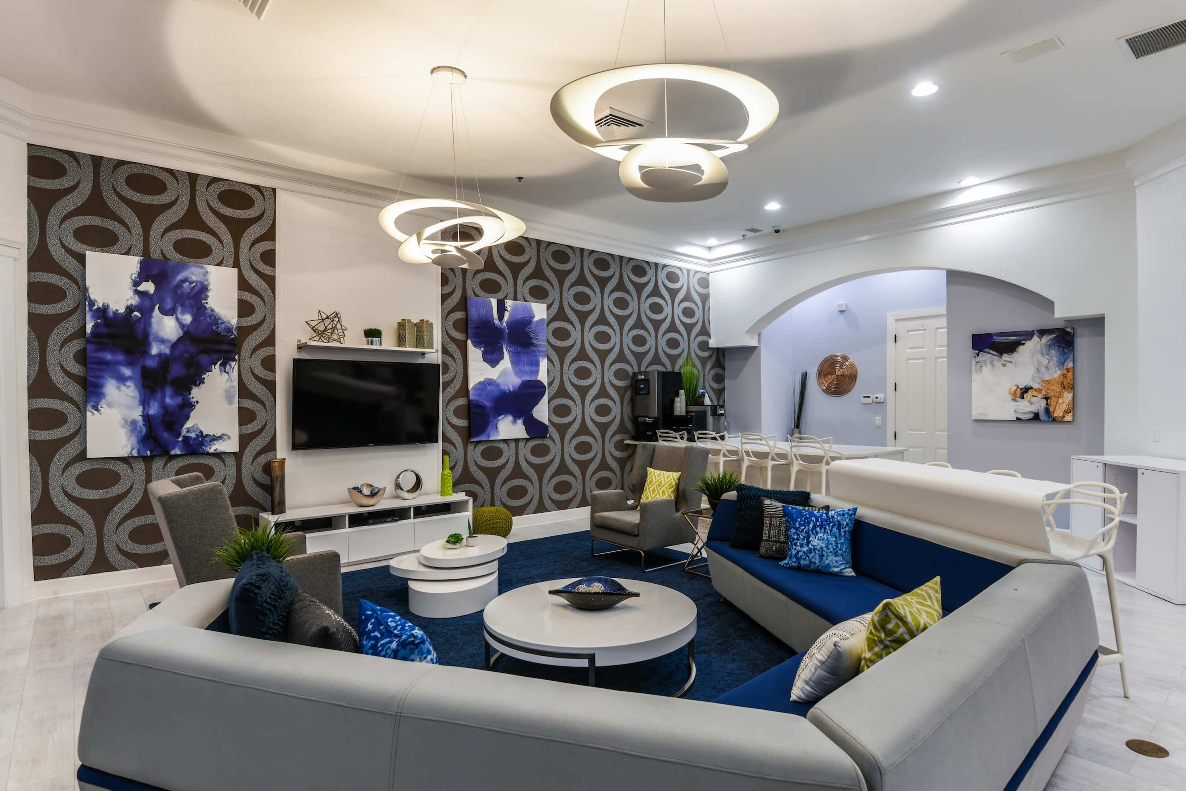The image shows a modern, stylish living area featuring a round sofa, circular light fixtures, and abstract wall art.