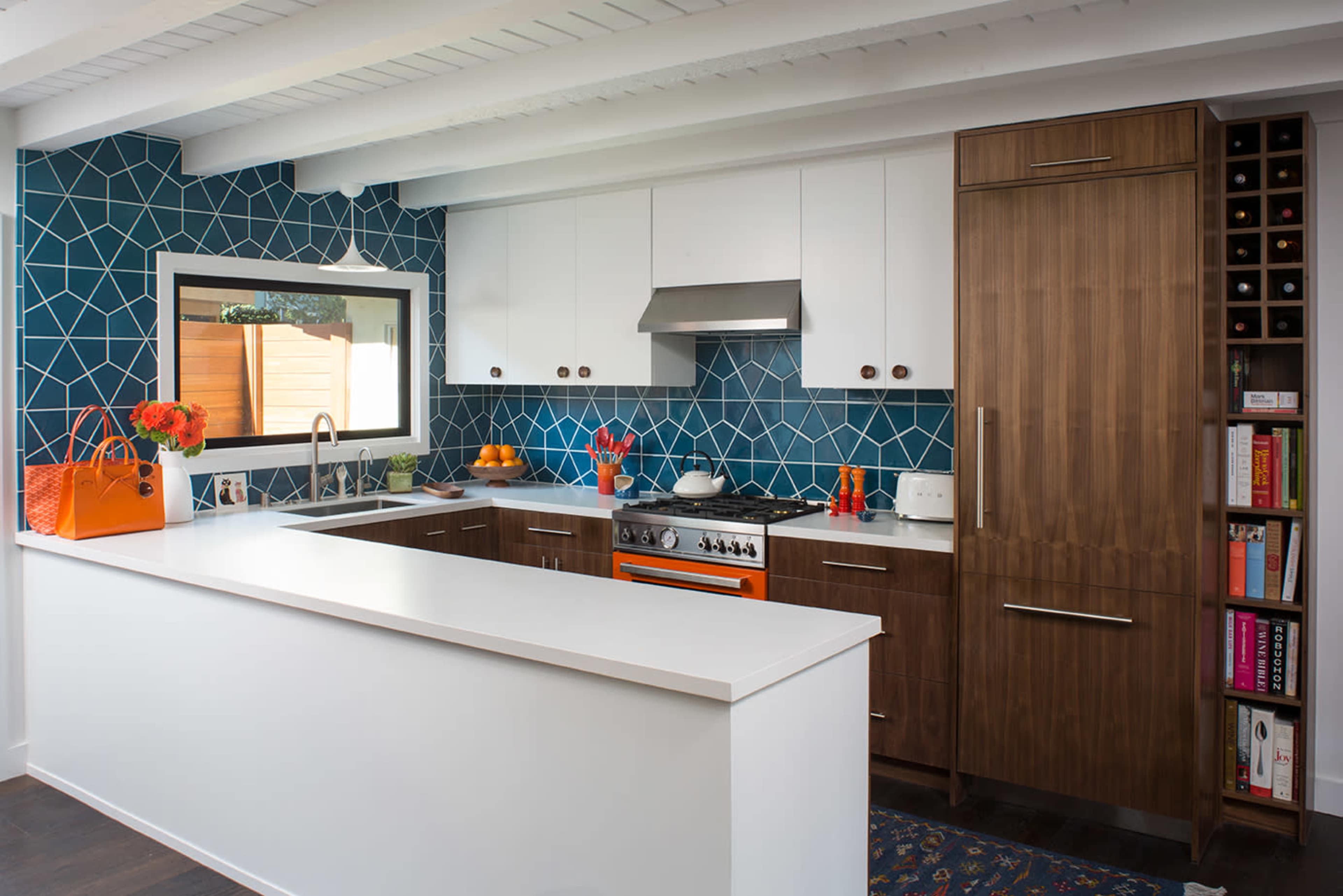 A modern kitchen features a dark wood cabinet, stainless steel appliances, and a blue geometric tile backsplash.