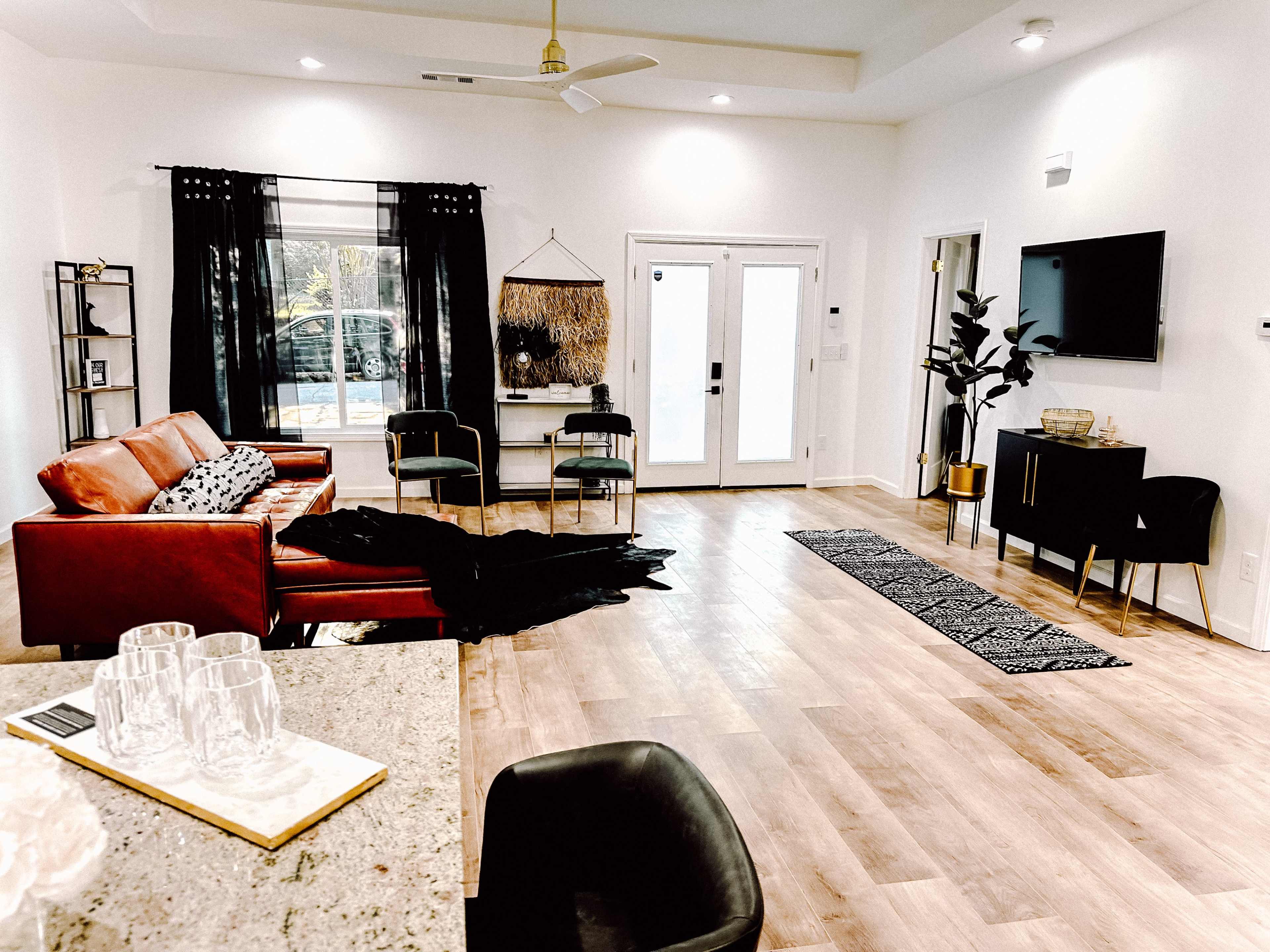 A modern living room with a red leather sofa, a black carpet, and a dining area that features a small black table and chairs.