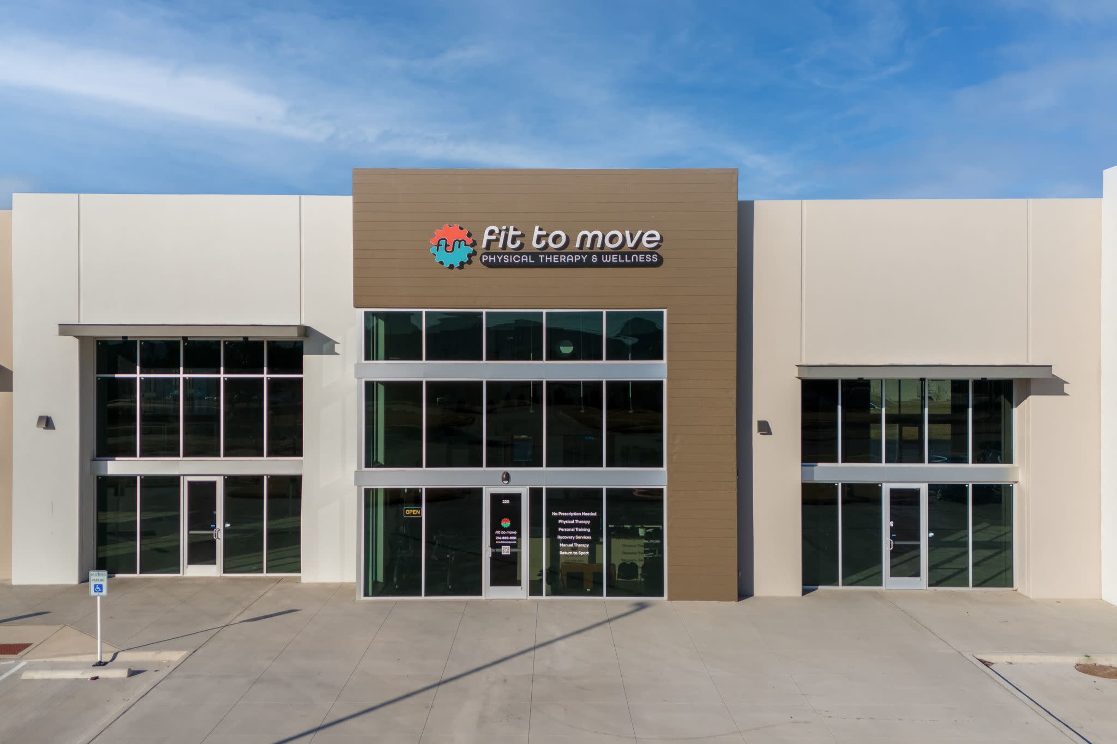 The image shows a modern building with large glass windows and a prominent sign reading "Fit to Move Physical Therapy & Wellness" on the front facade.