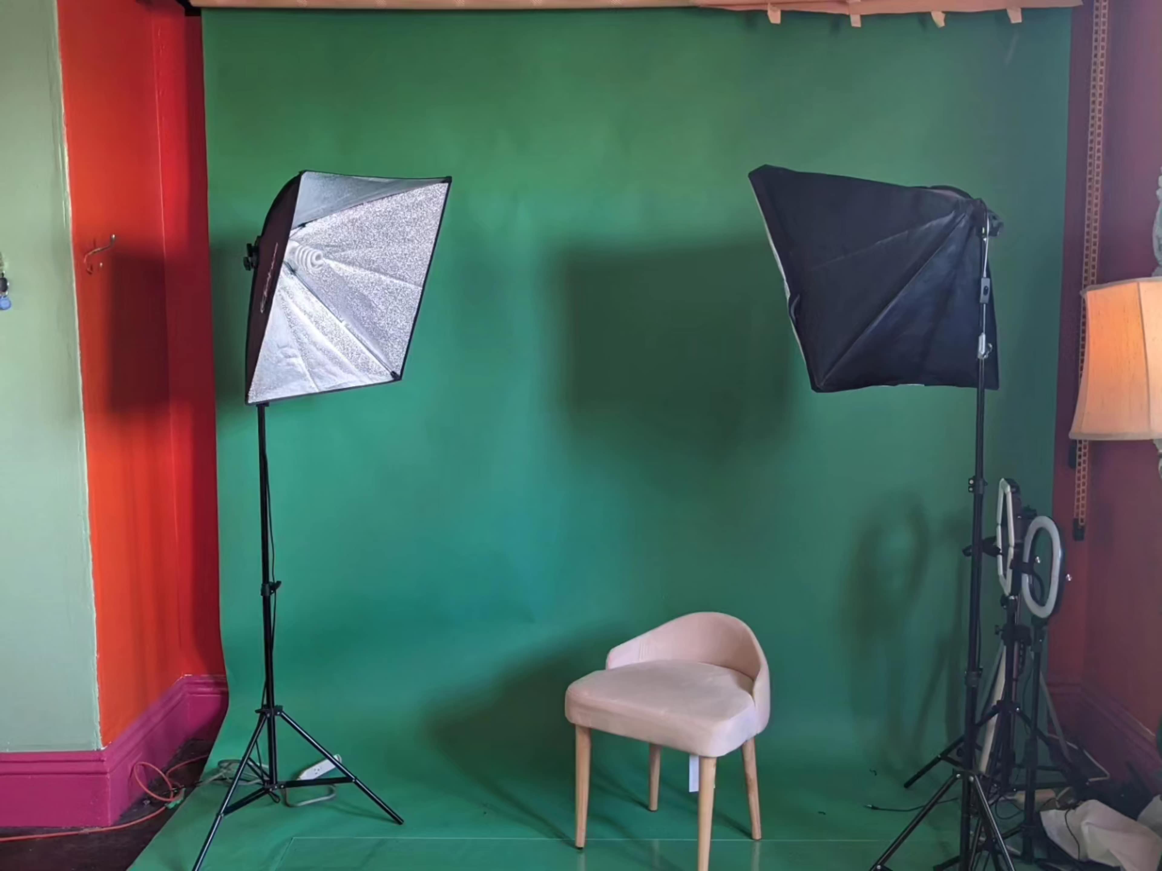 A green backdrop with two softbox lights and a single light-colored chair positioned in front.