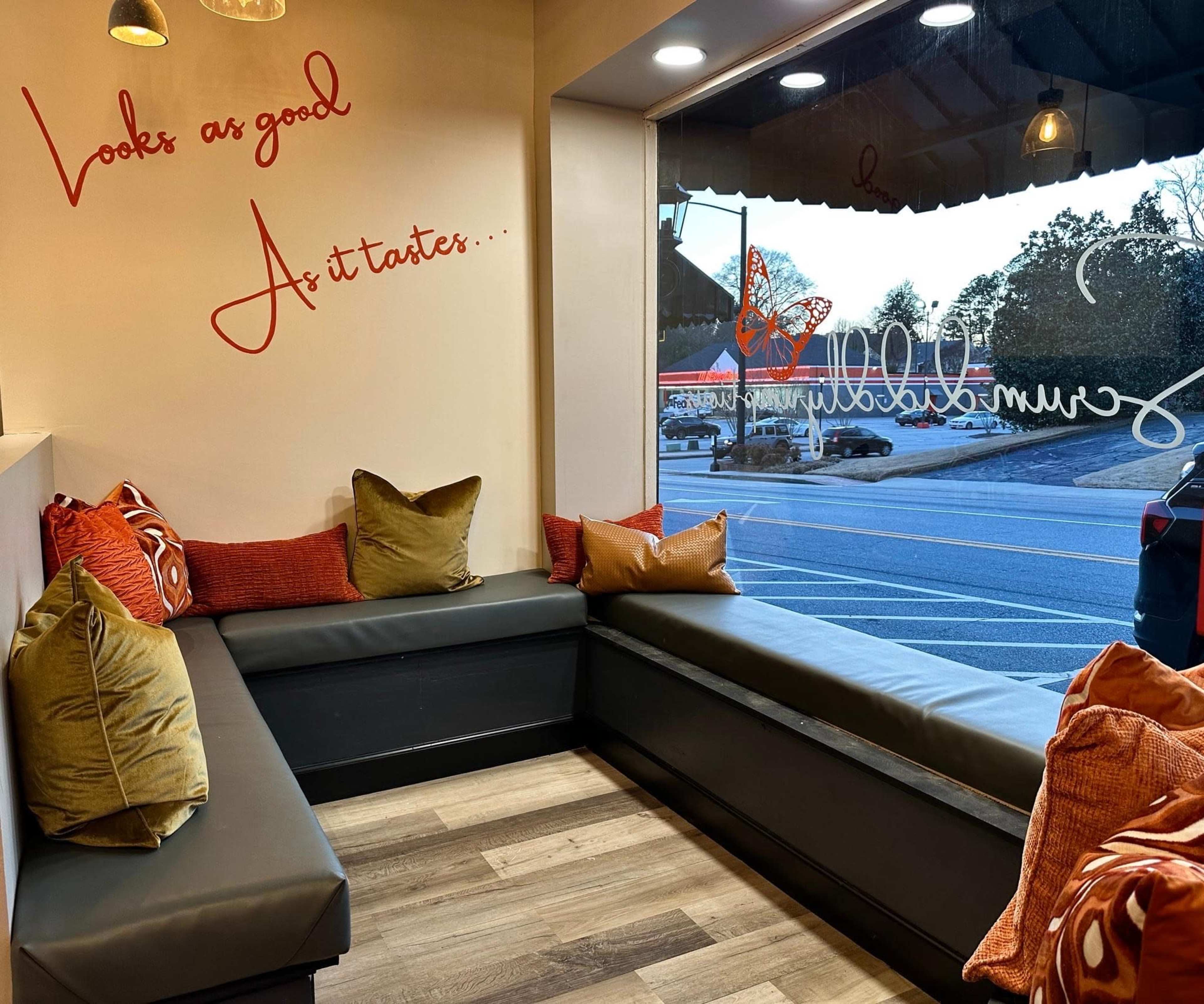 A cozy seating area with cushions in a café, featuring a large window that opens to a view of the outside.