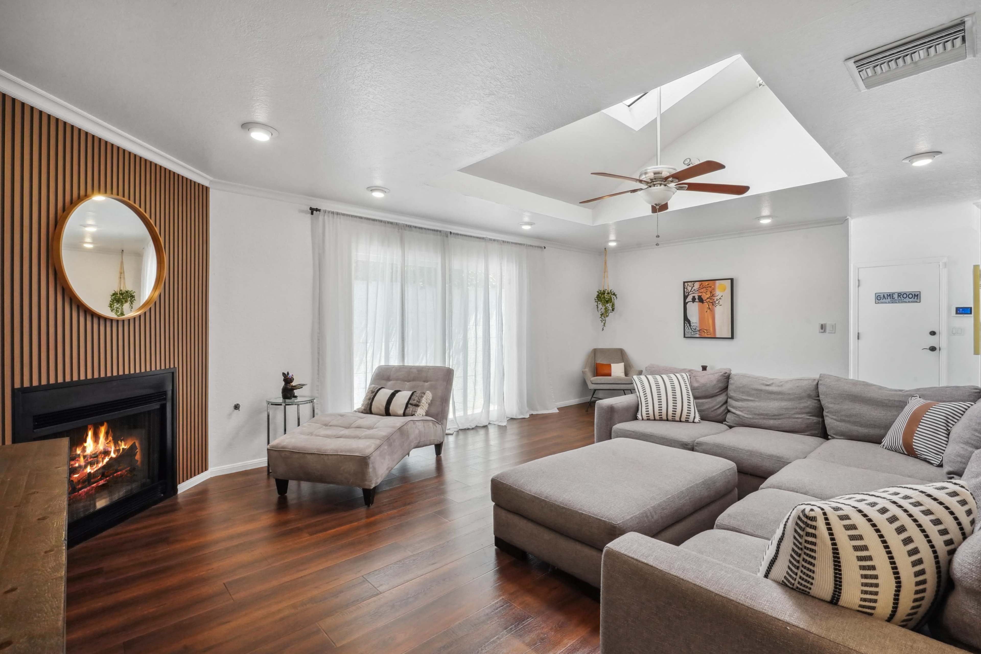 A spacious living room features a large sectional sofa, a fireplace, and natural light streaming through a skylight.