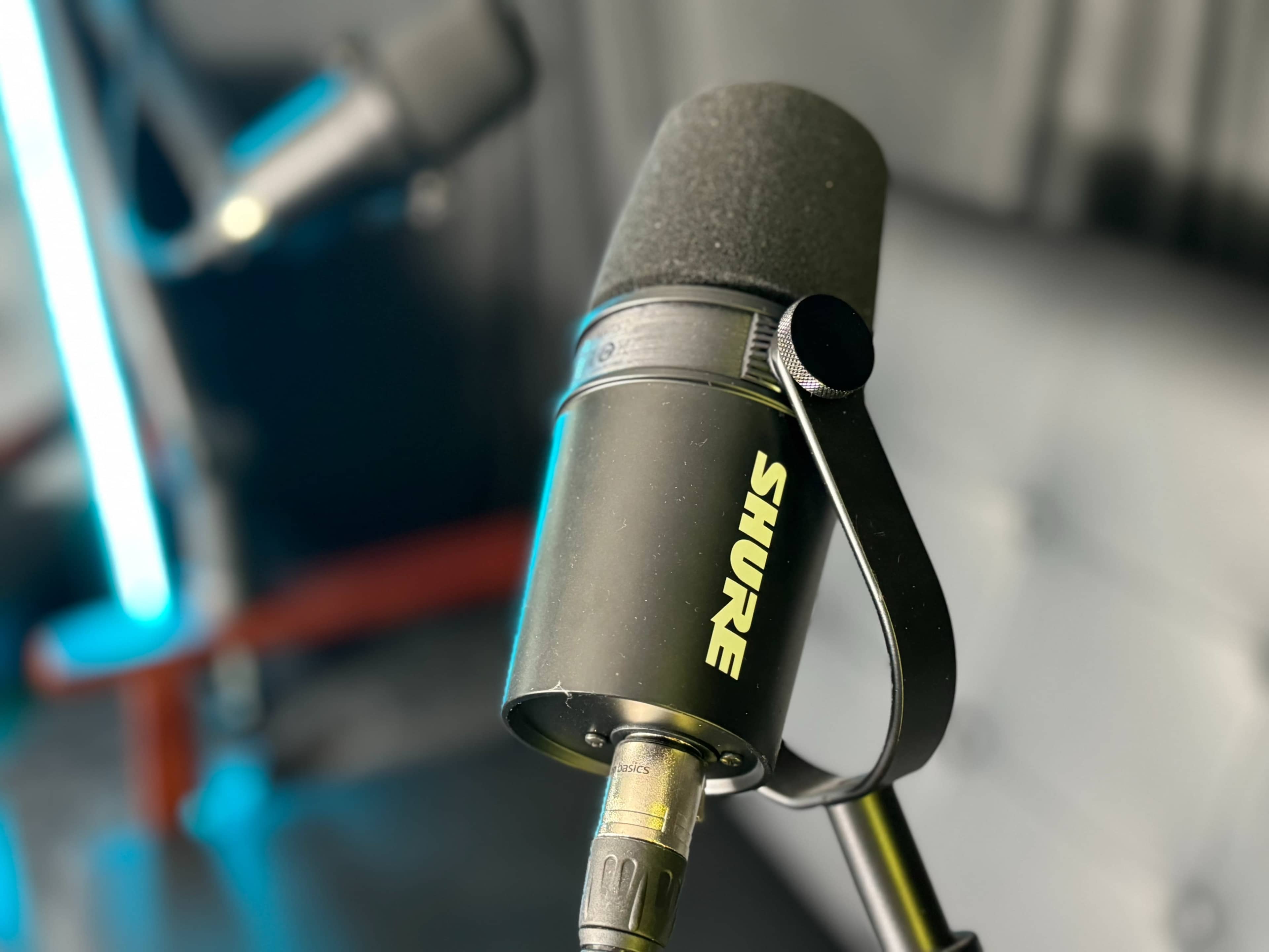 A close-up of a Shure microphone mounted on a stand amidst a blurred background.