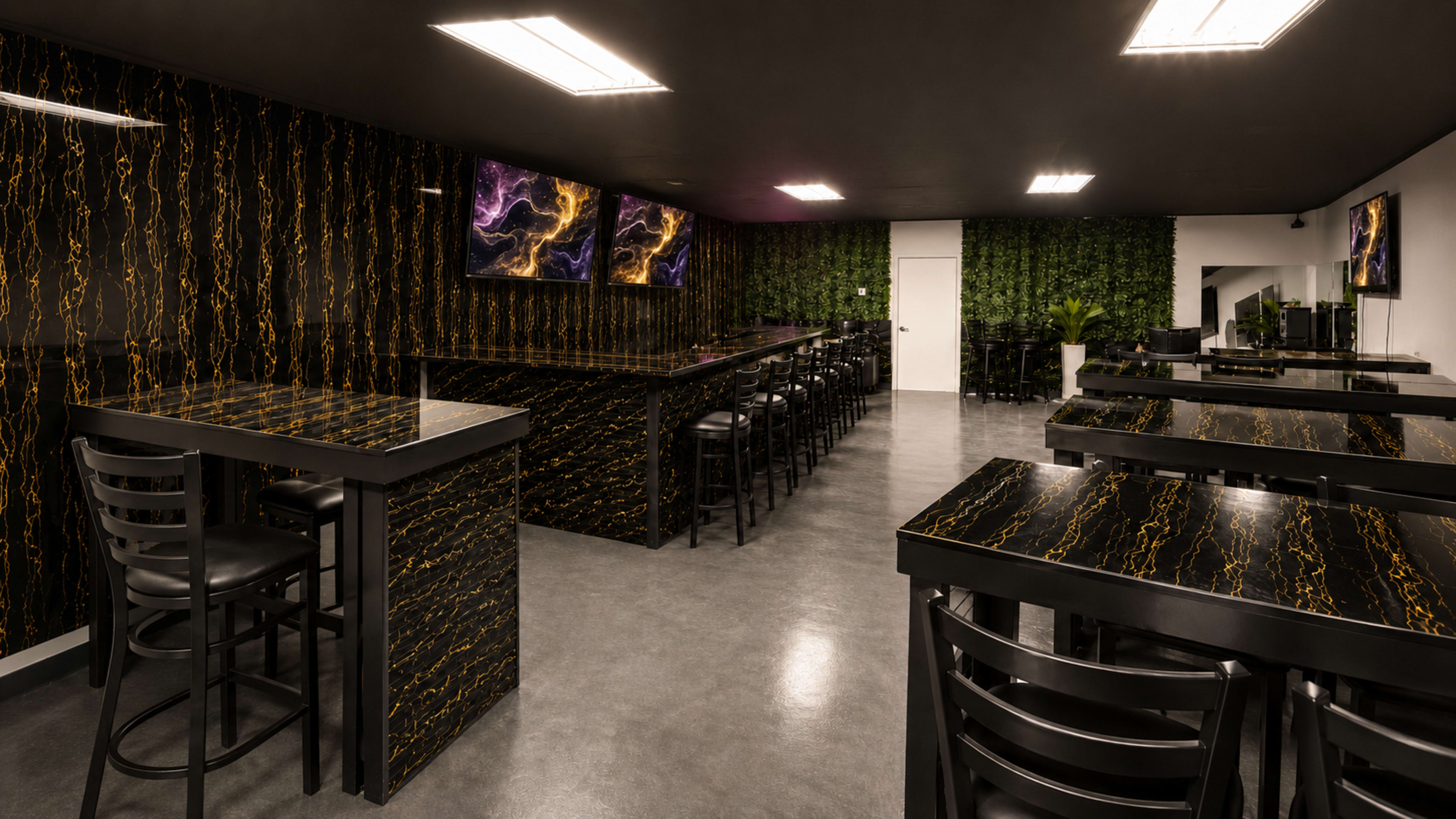 The image shows a modern, spacious interior of a restaurant or cafe featuring black marble tables, dark walls with a gold veining pattern, and green foliage accents.