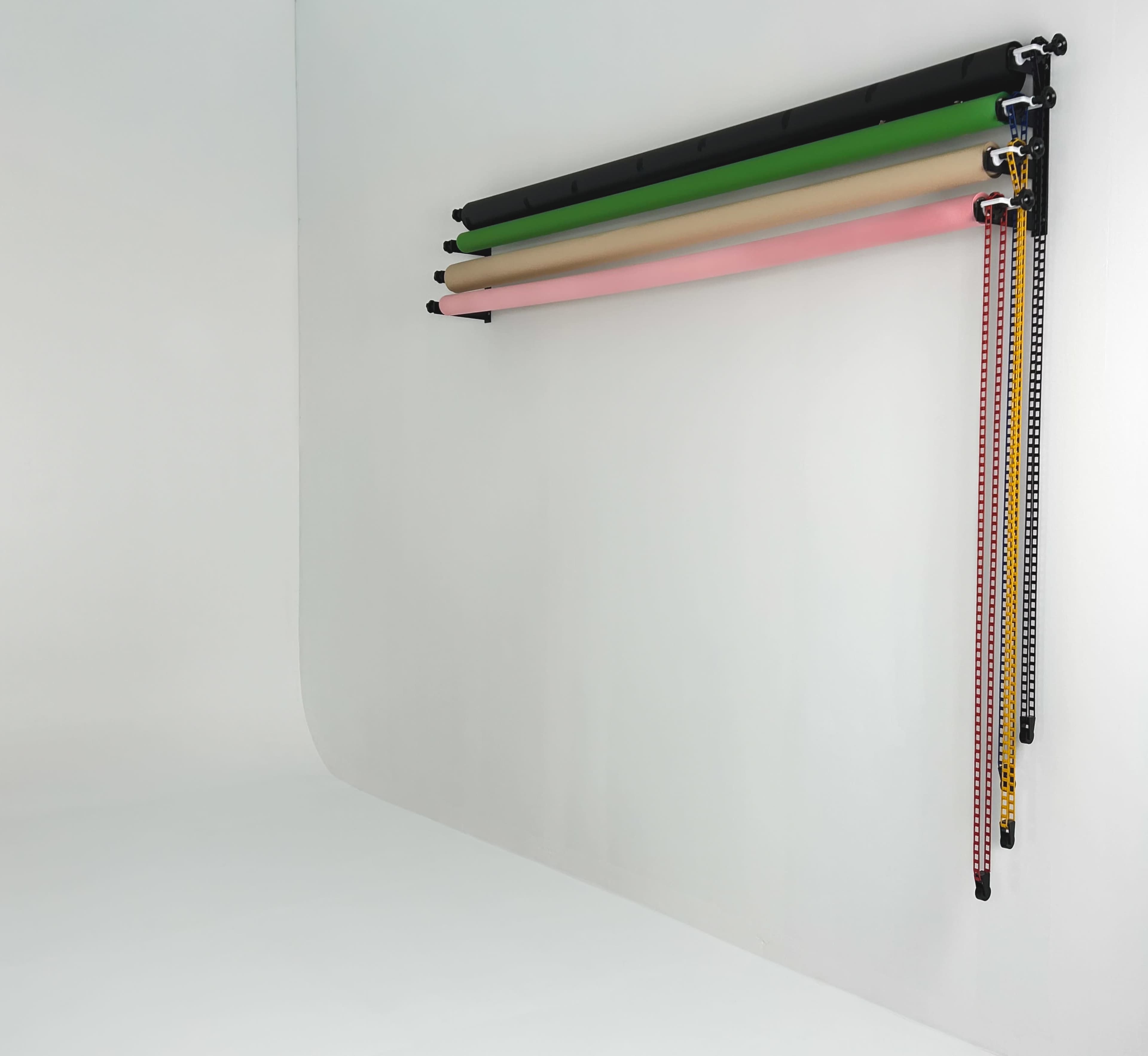 A series of colored backdrop rolls are mounted on a wall, with various color options visible above a smooth, white surface.