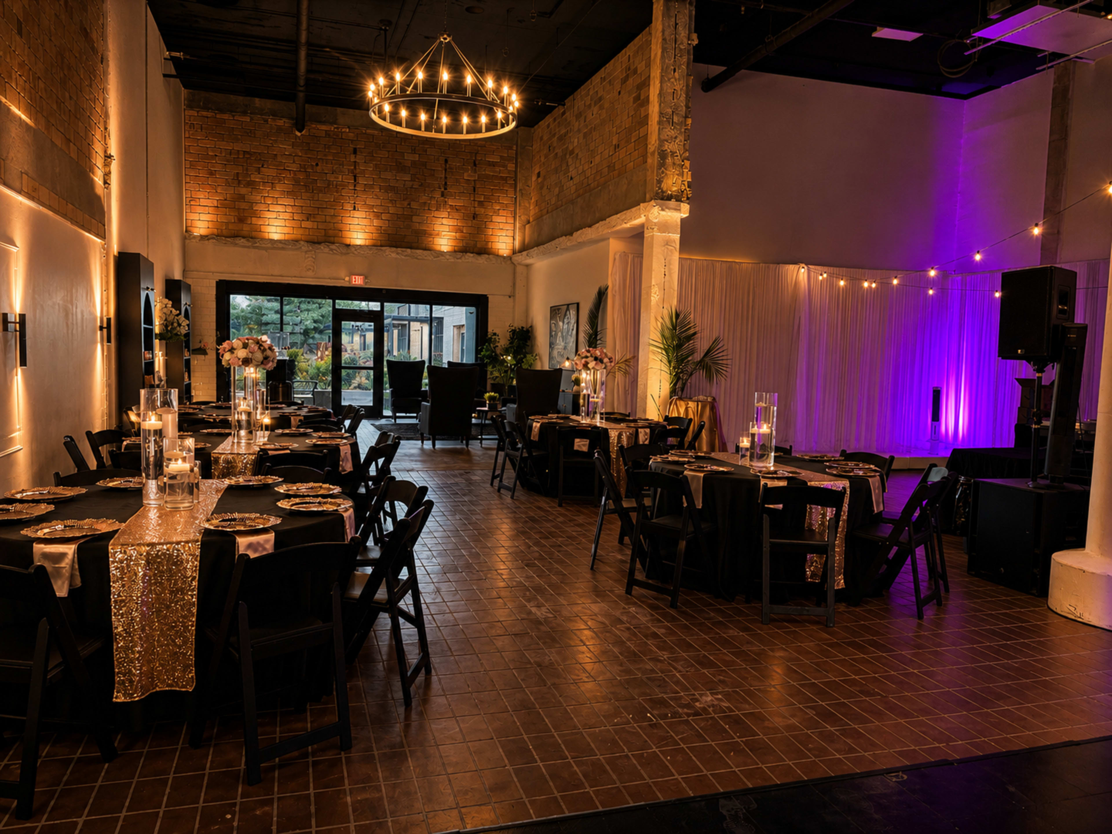 The image shows a well-decorated event space with black tables, golden table runners, and ambient lighting.