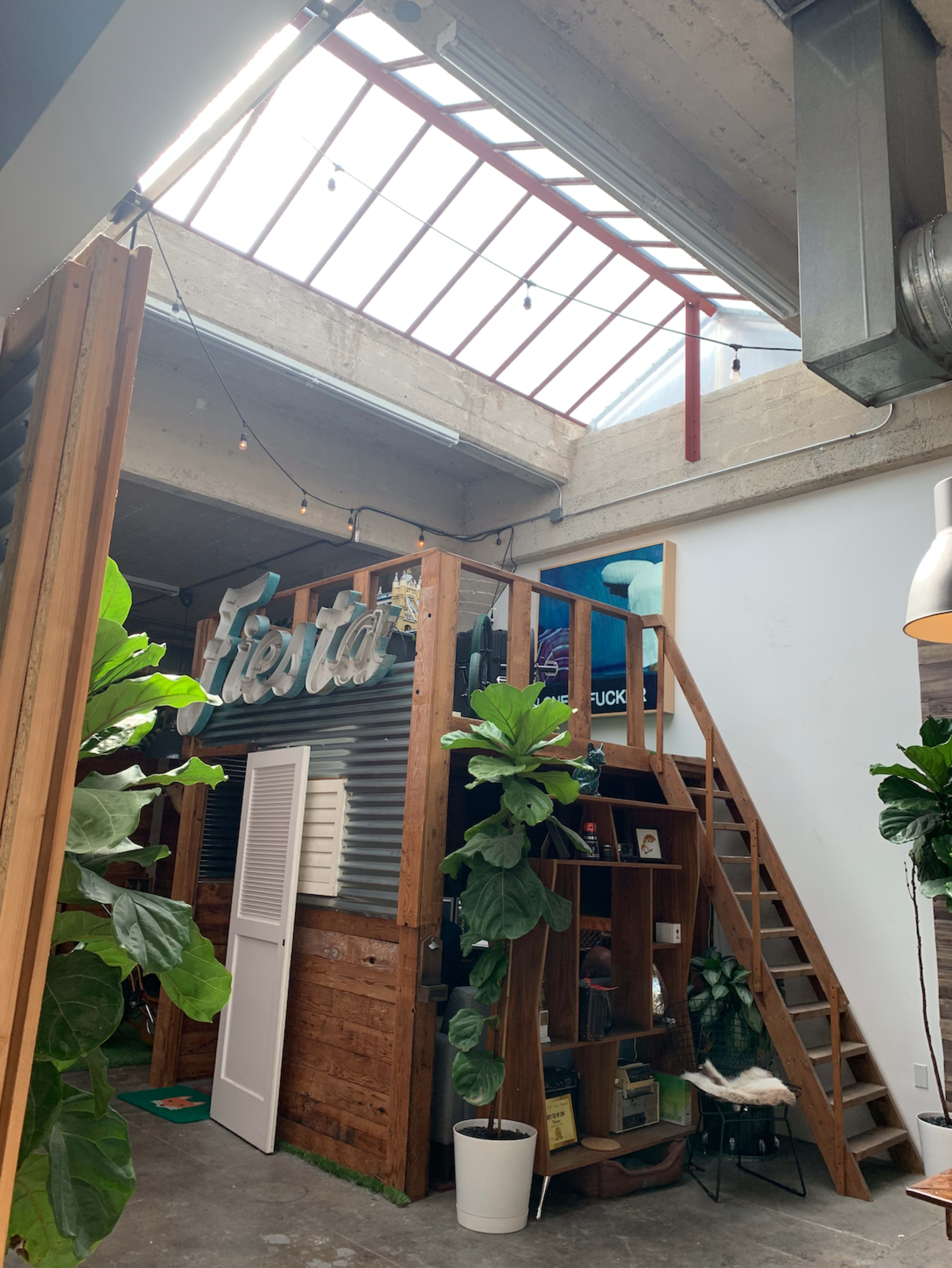 A modern interior with a staircase leading to a loft area, surrounded by greenery and industrial-style decor.