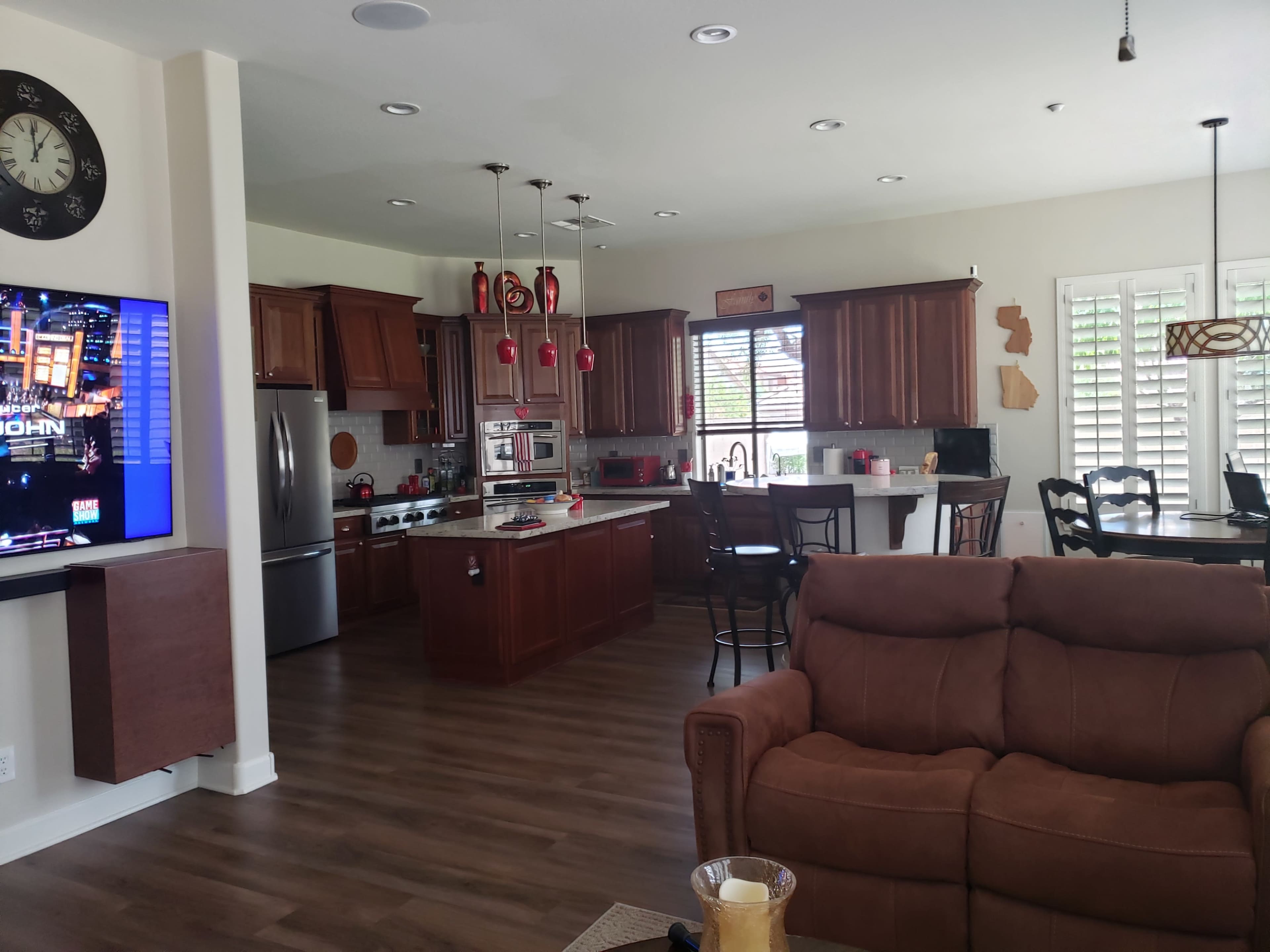 A modern kitchen and living area featuring dark wooden cabinetry, stainless steel appliances, and a seating area with a brown couch.