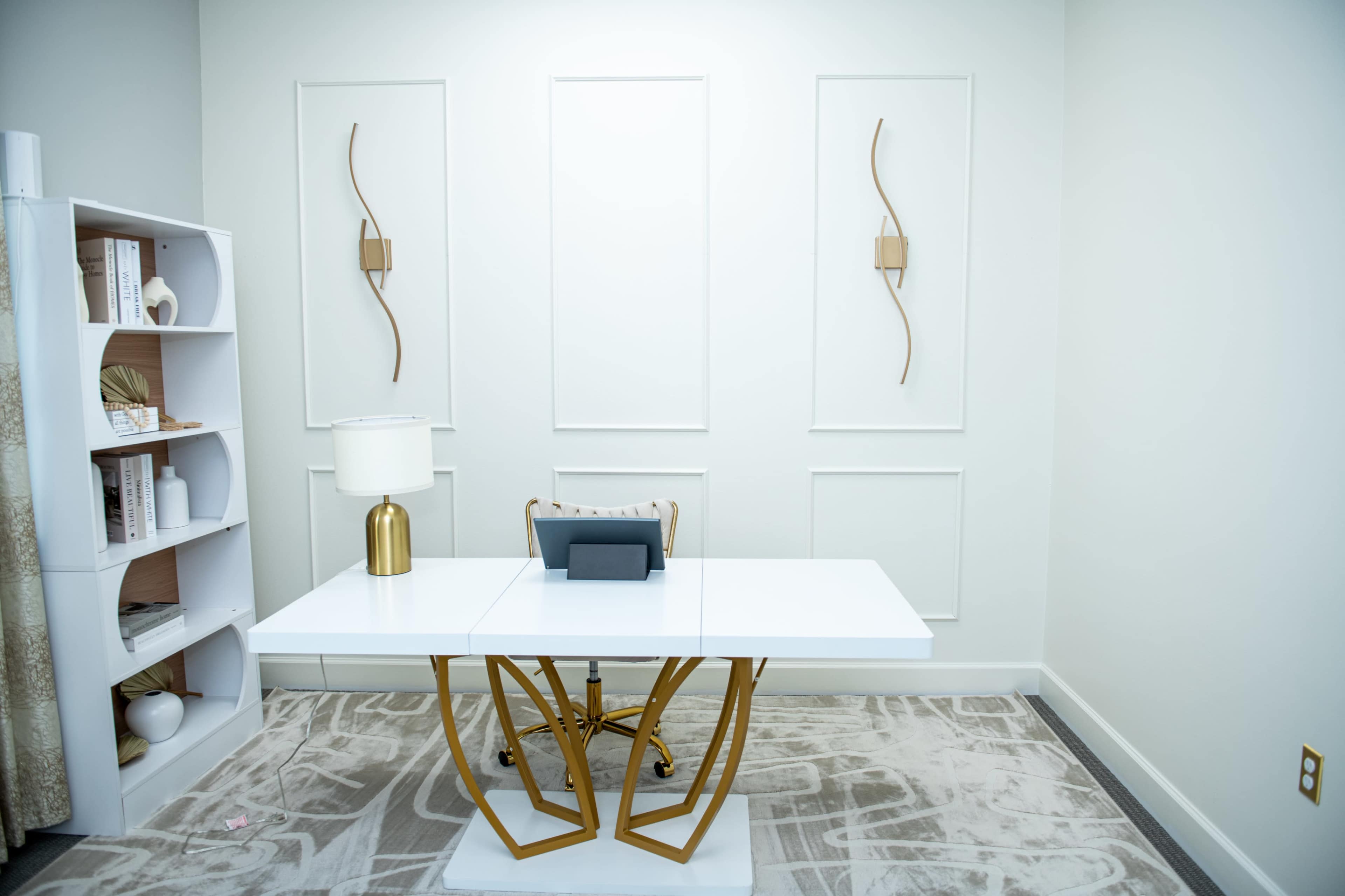 The image shows a modern office with a white desk and a decorative wall featuring minimalist light fixtures.