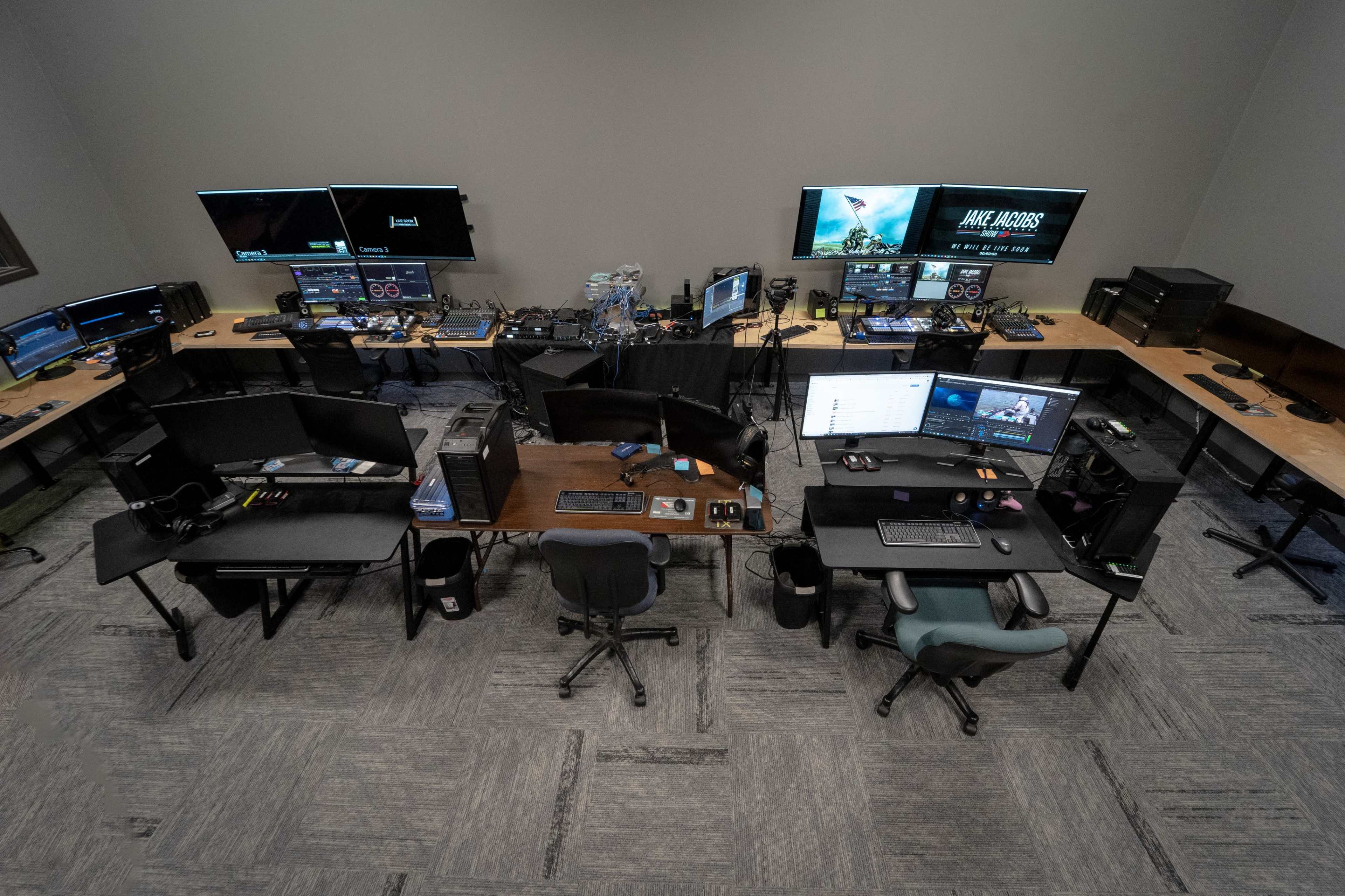 The image shows a large room with multiple computer desks equipped with monitors, keyboards, and gaming peripherals arranged in a grid layout.