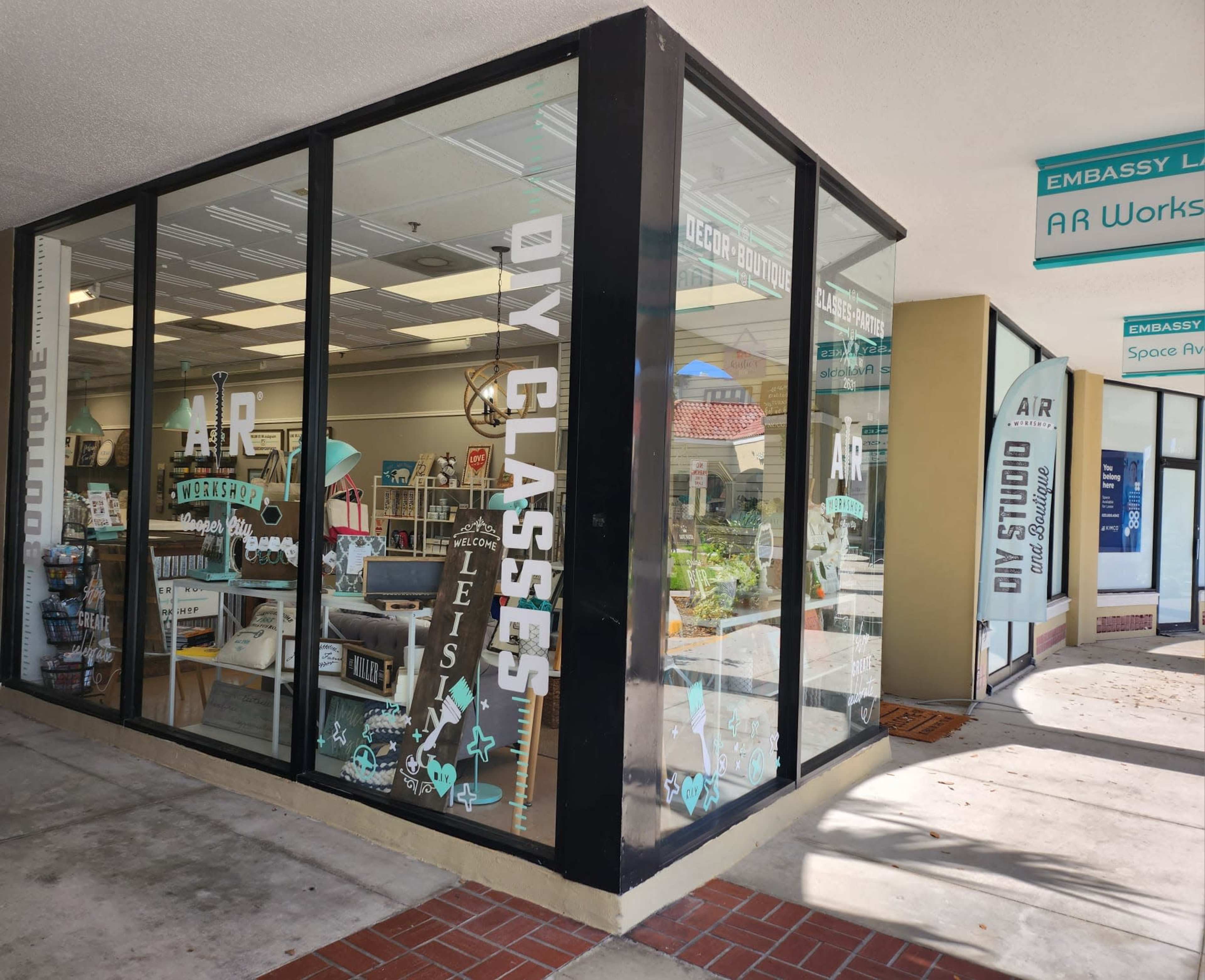 The exterior of a storefront featuring large glass windows that display various craft supplies and a sign indicating "DIY Classes."
