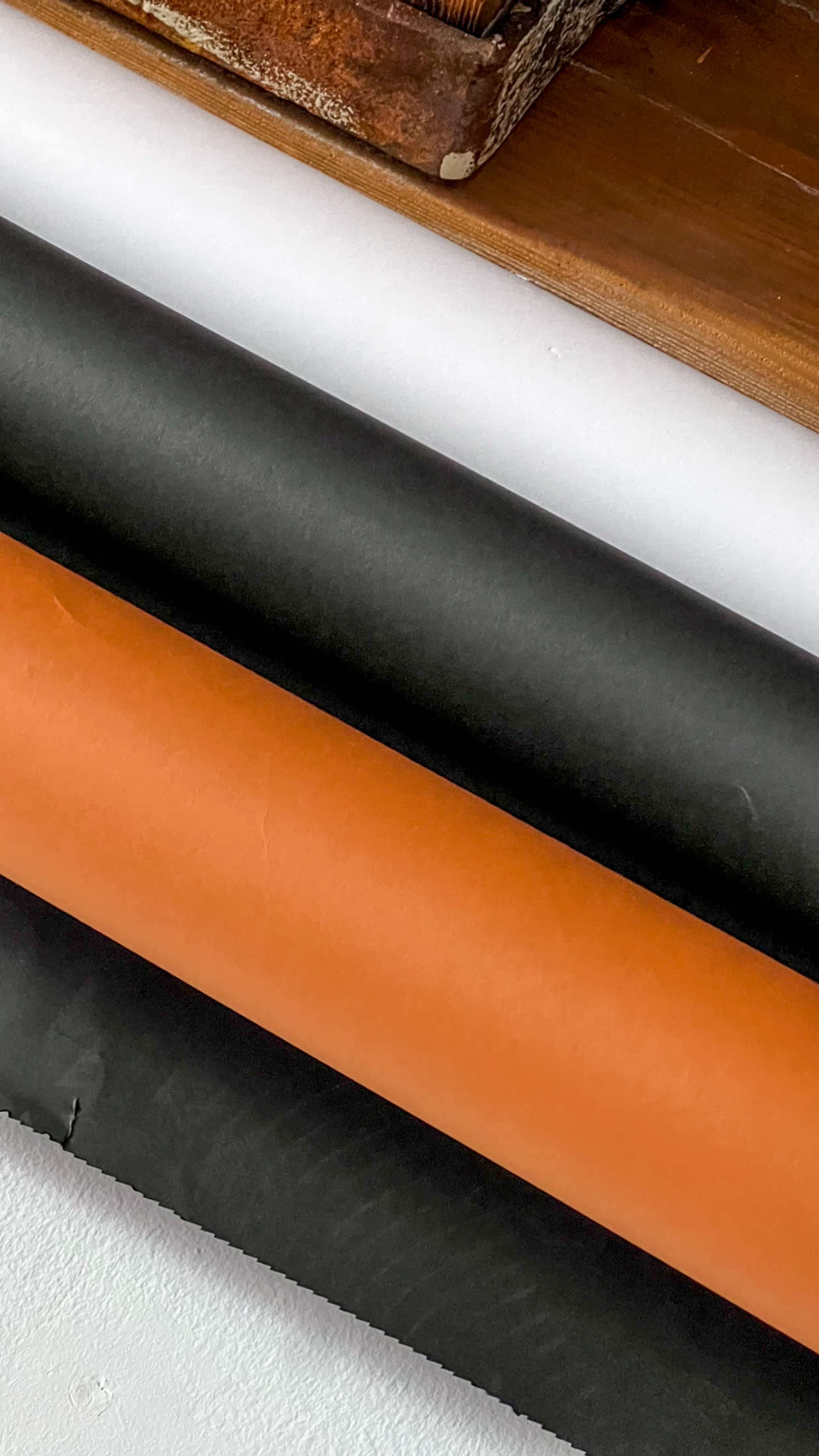 Rolls of paper in orange, black, and white stacked on a surface.
