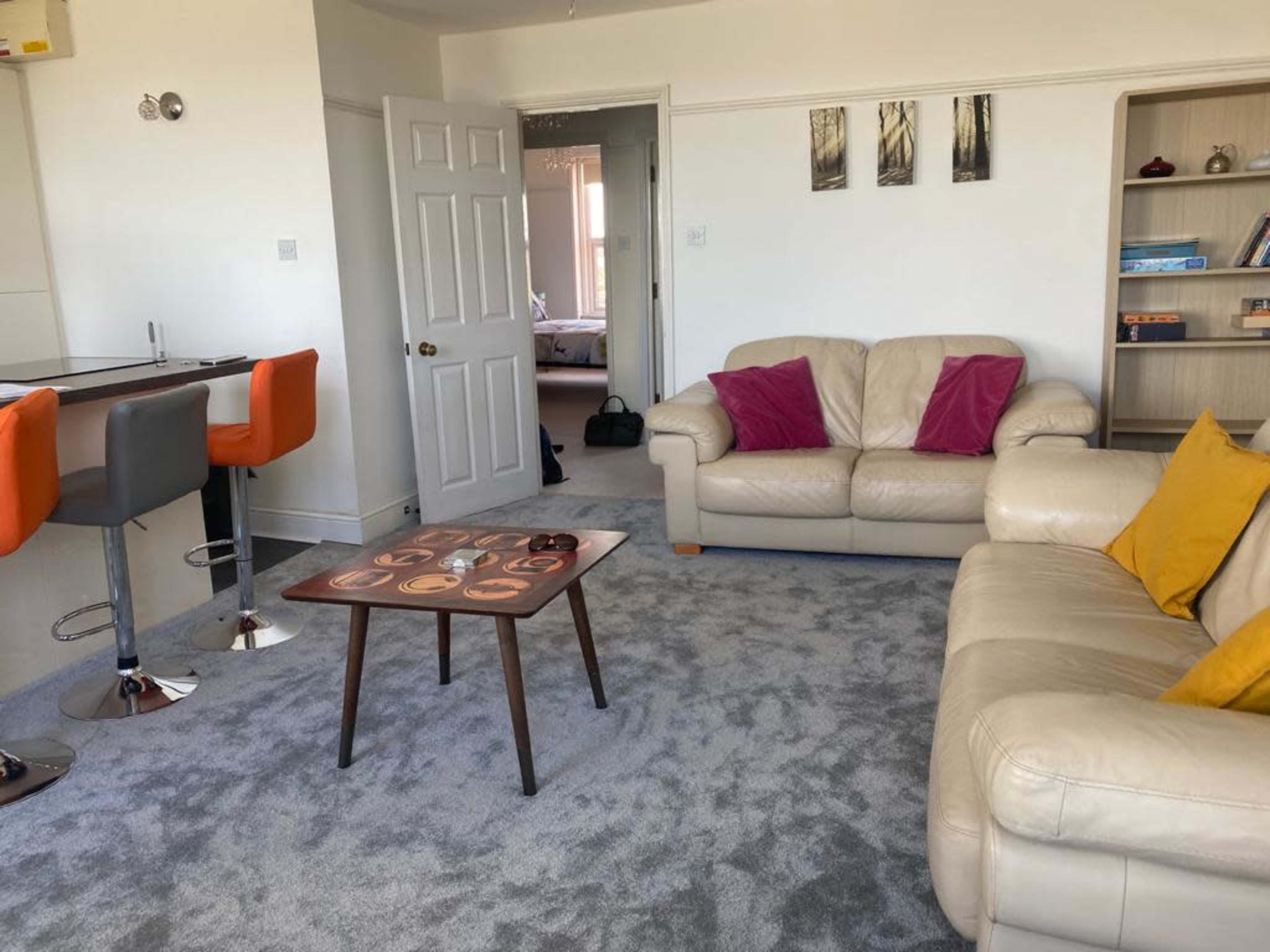 A living room with two leather sofas, a wooden coffee table, and a bar area with high stools.