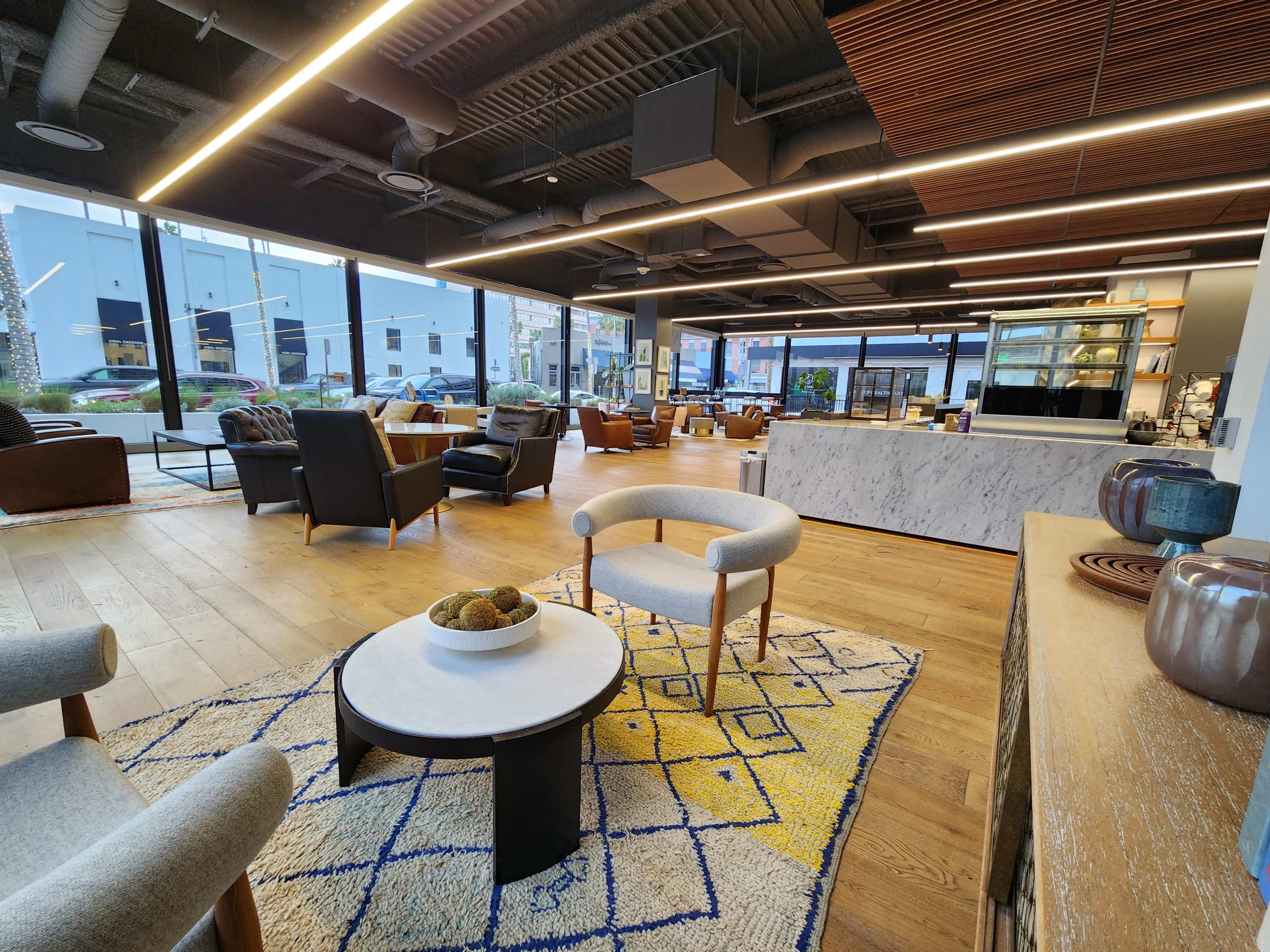 A modern lounge area with comfortable seating, a coffee bar, and large windows allowing natural light to enter.