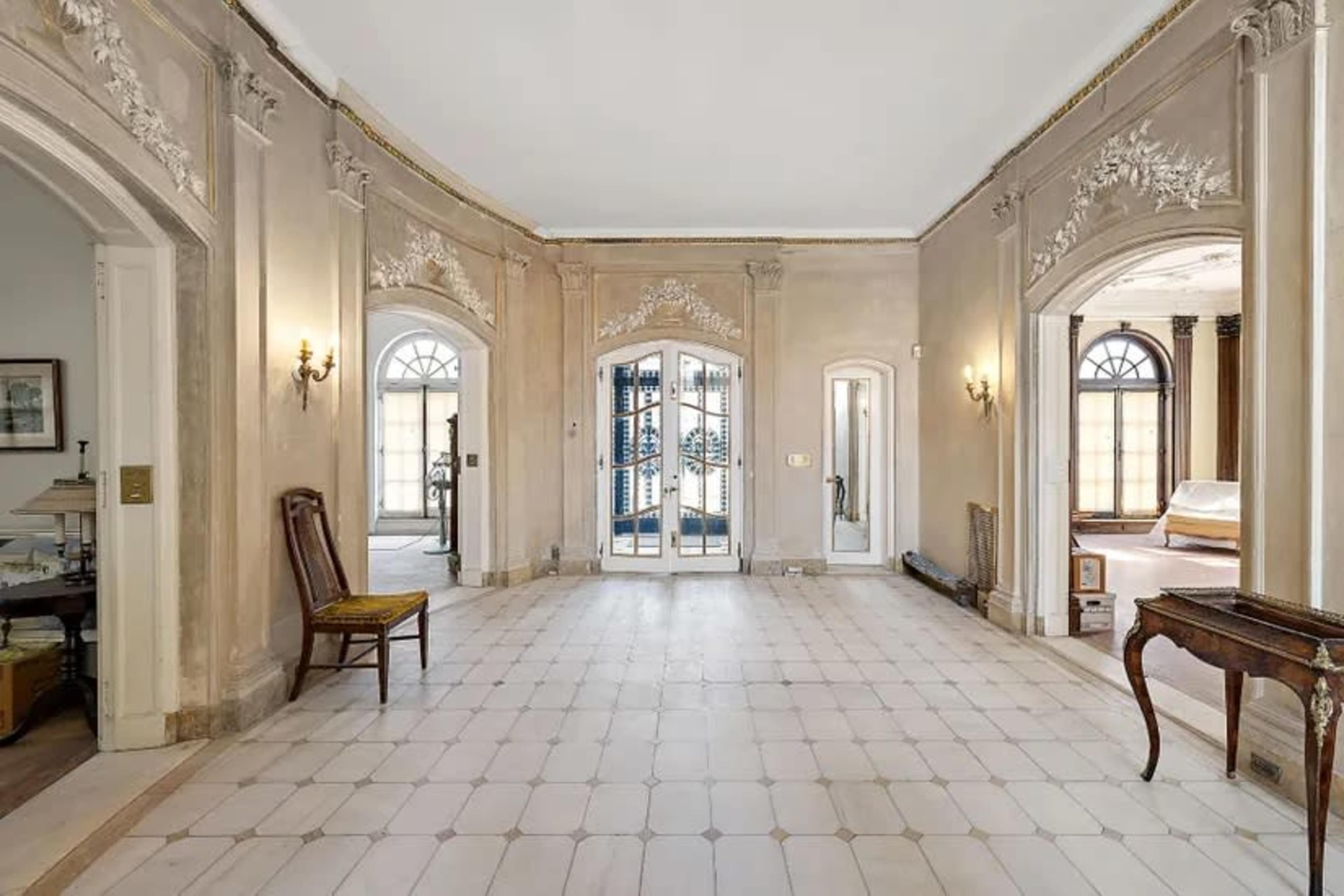 The image shows a spacious, elegantly designed hallway featuring arched doorways and decorative wall molding.