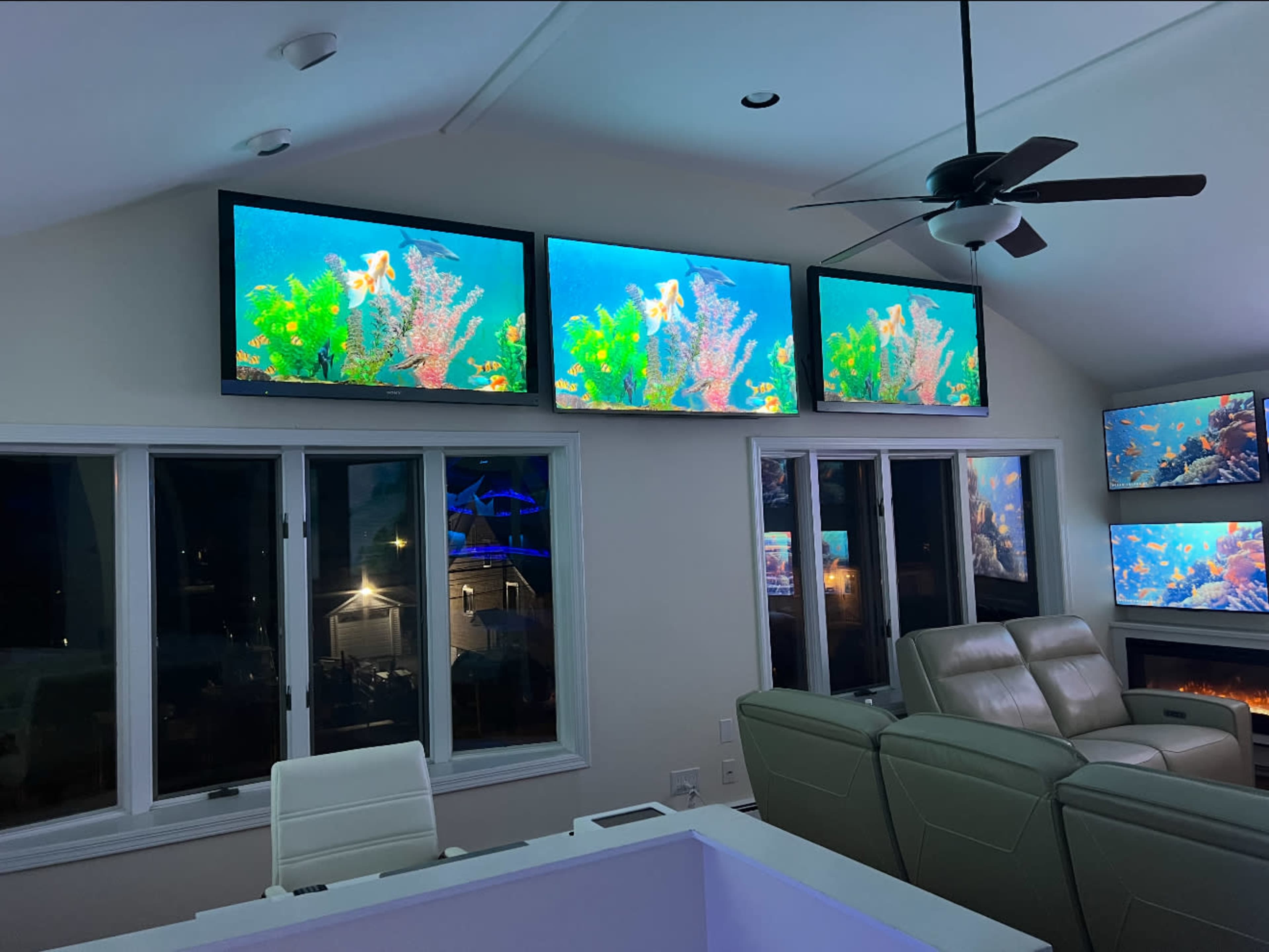 The room features multiple large screens displaying vibrant underwater scenes, with modern furniture and large windows visible.