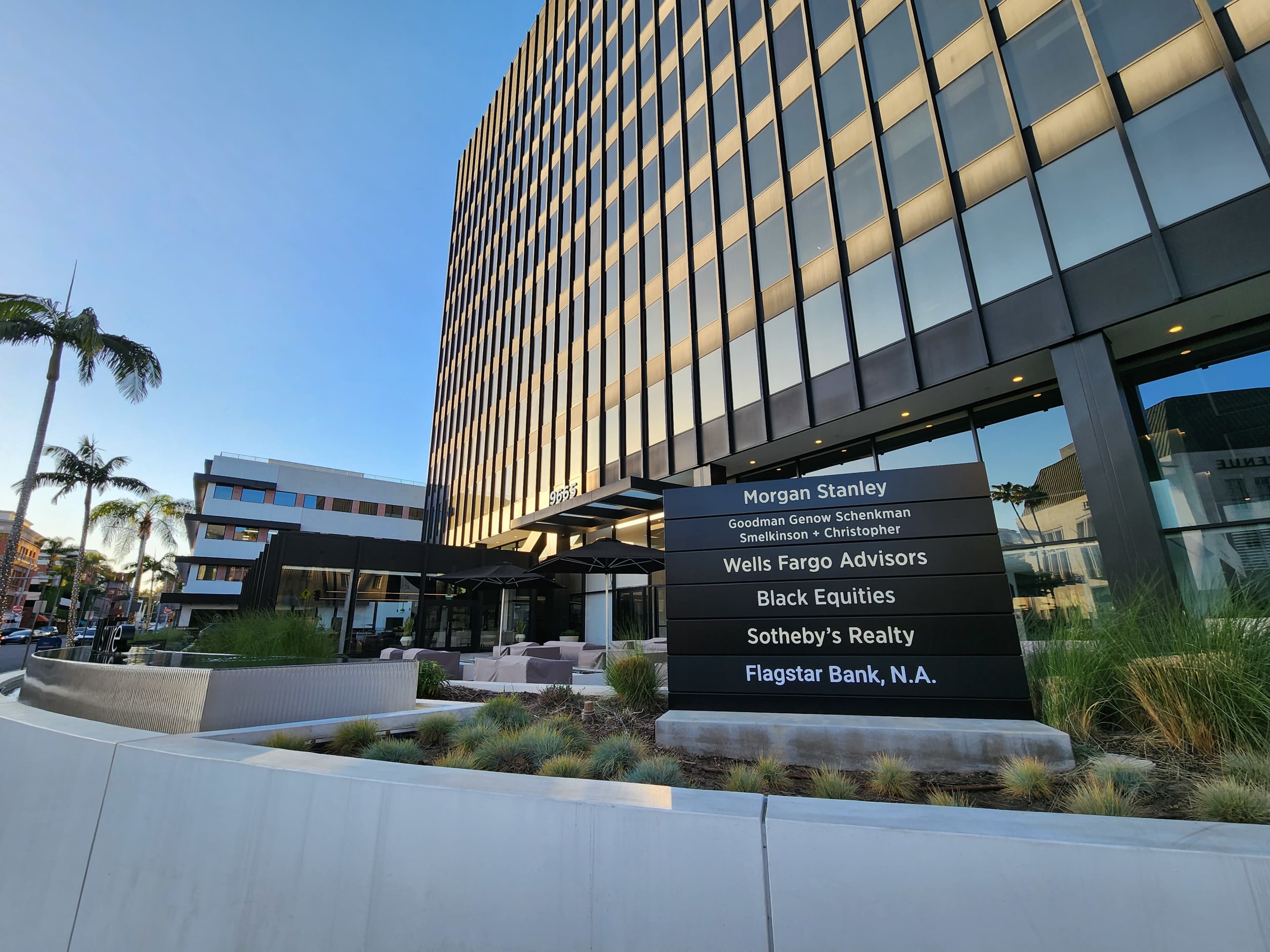 A modern building facade featuring various corporate signage, including Morgan Stanley, Wells Fargo Advisors, and Flagstar Bank, among others.