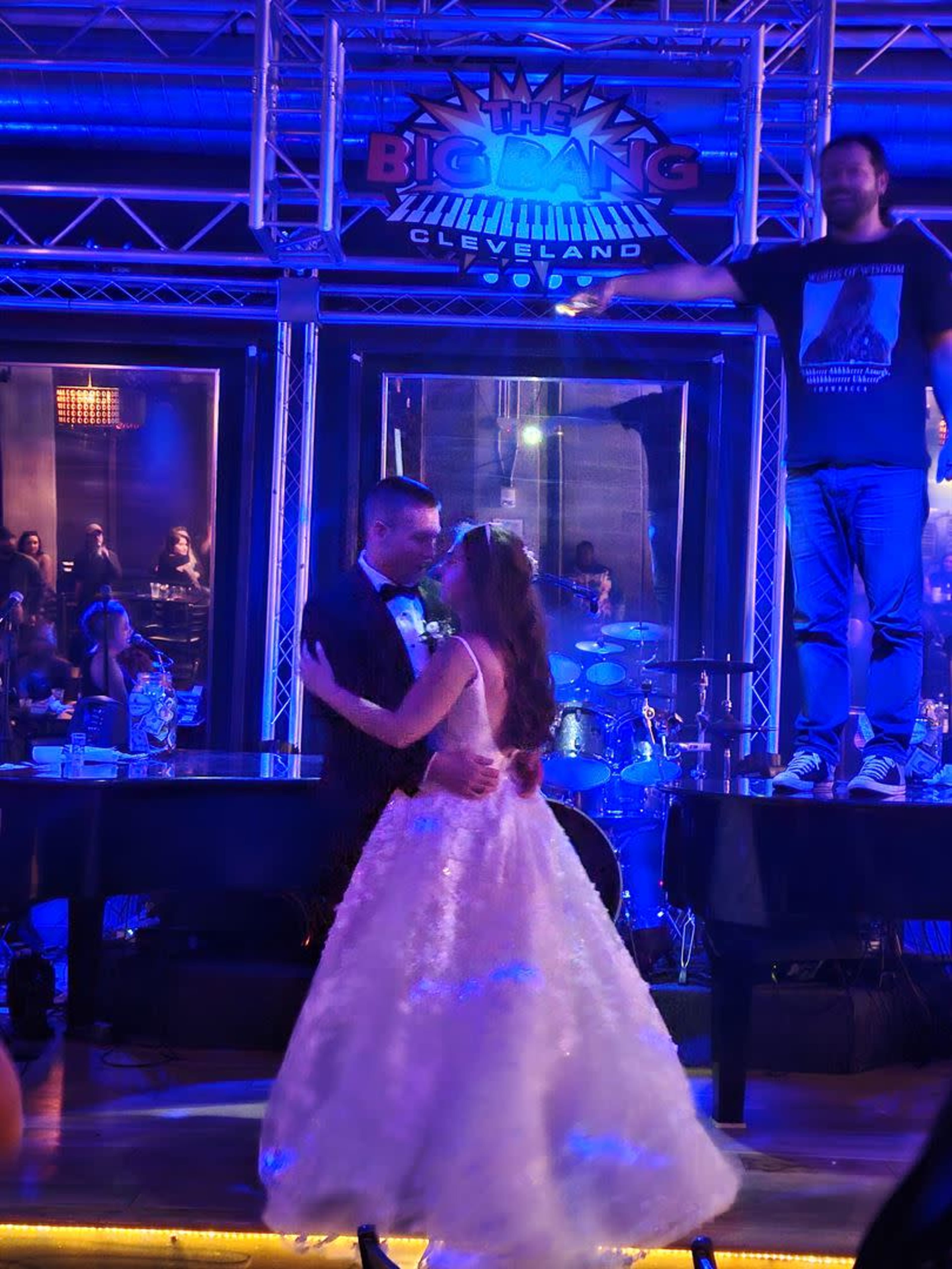 A bride and groom dance together on a stage in front of a live band at a venue called The Big Bang in Cleveland.