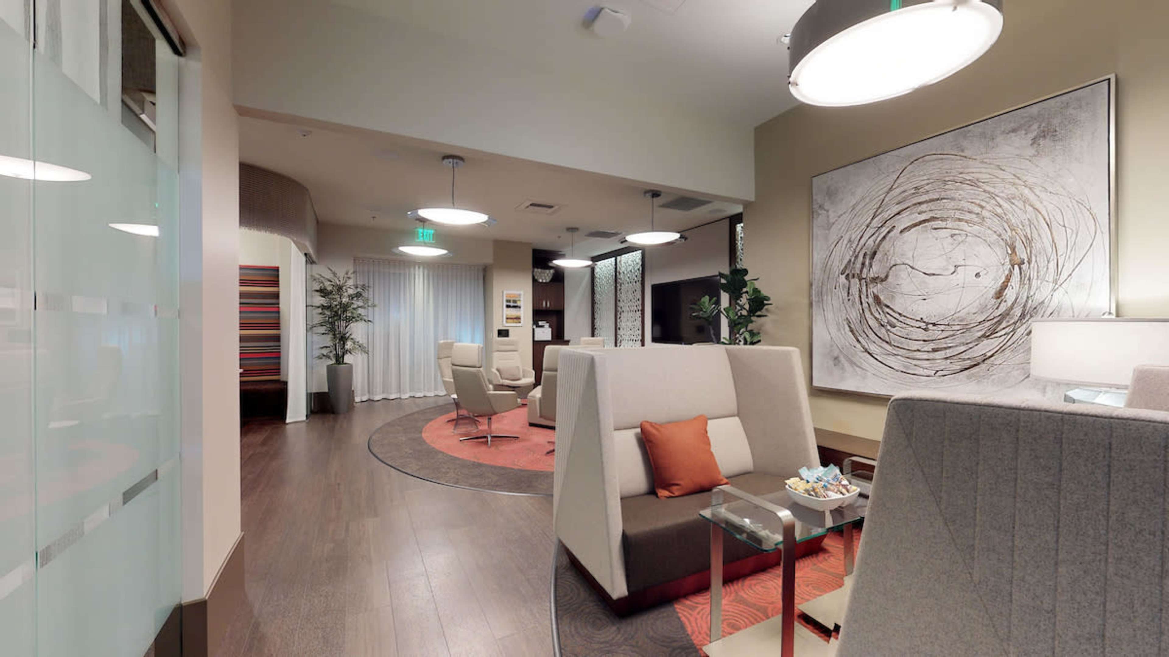 A modern lounge area with seating, abstract artwork on the wall, and soft lighting, creating a comfortable atmosphere.