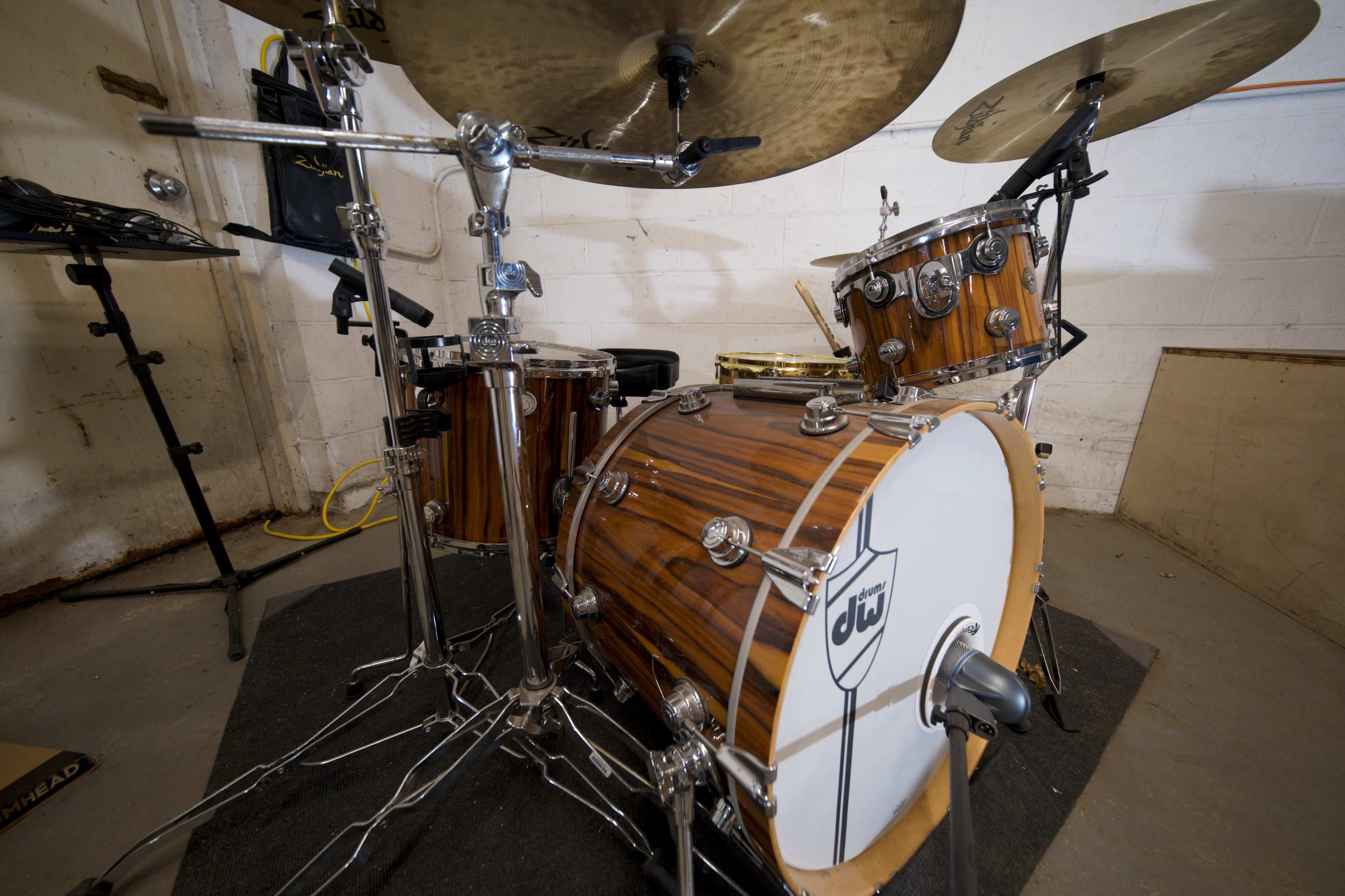 A close-up view of a brown wooden drum kit with chrome hardware and a cymbal positioned above it.