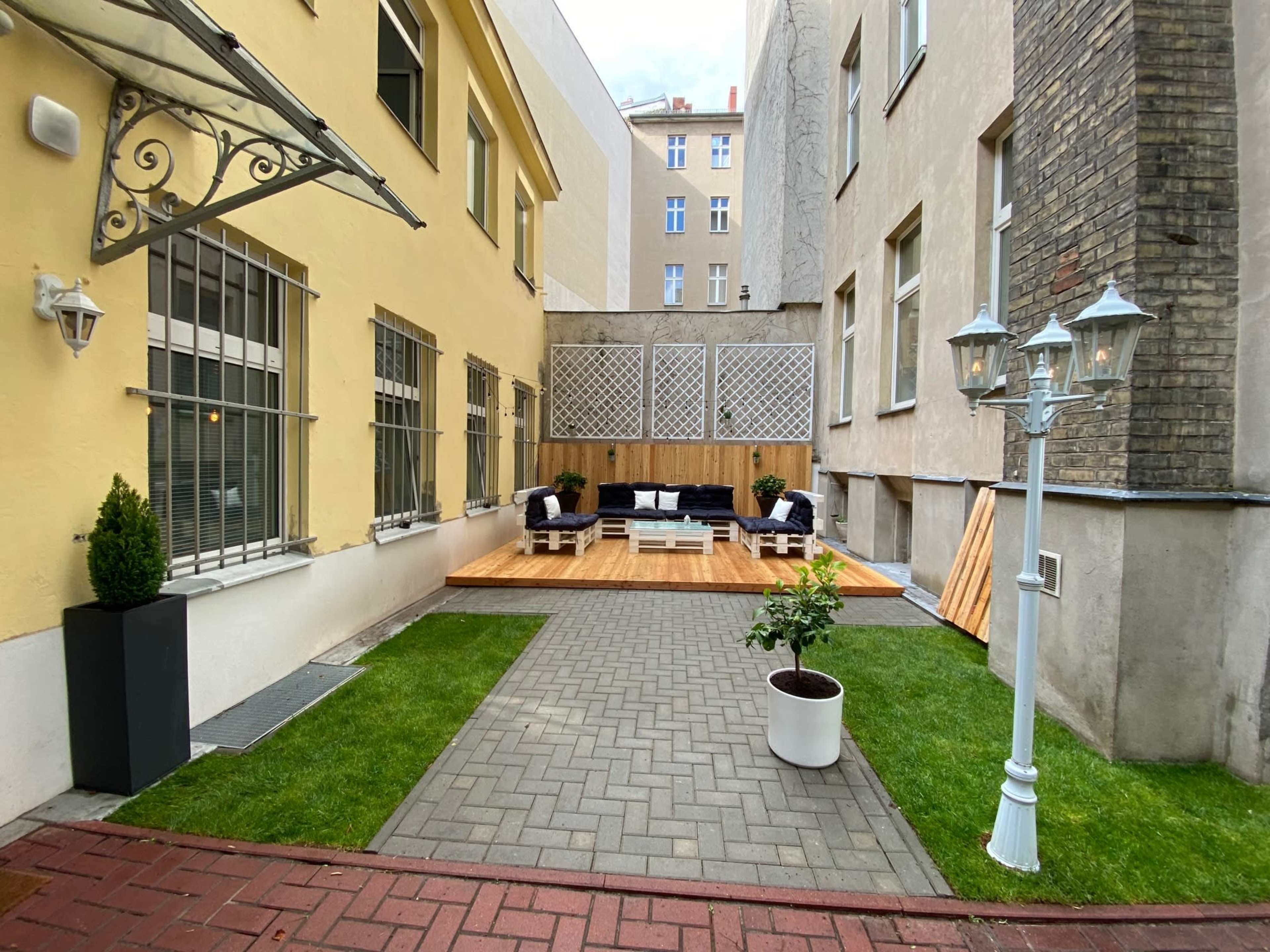 A courtyard area with a wooden deck, outdoor seating, landscaped grass, and a decorative lamp post.