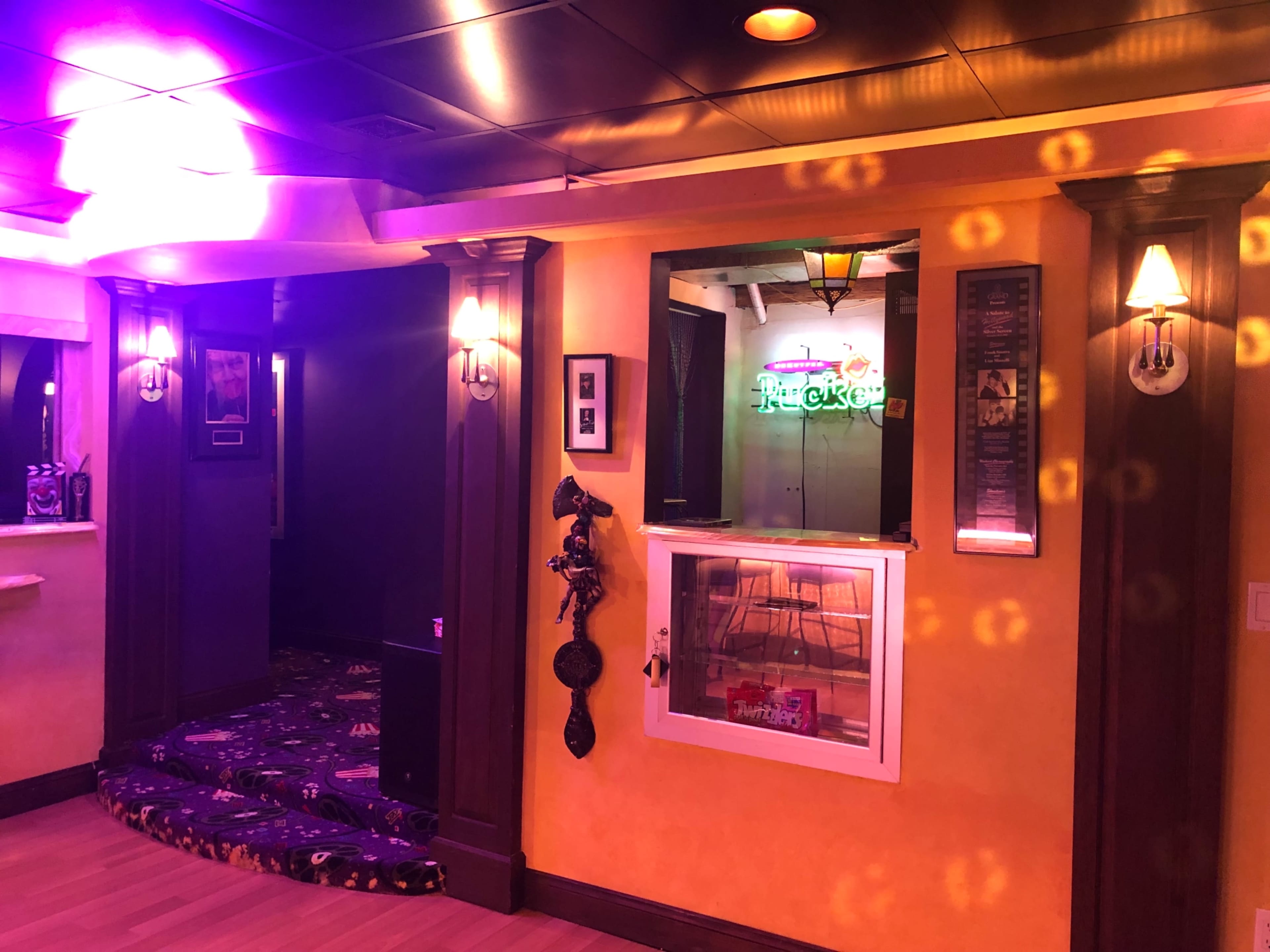 The interior of a vibrant recreational space features a glowing bar area with neon signage, illuminated walls, and stylish lighting fixtures.