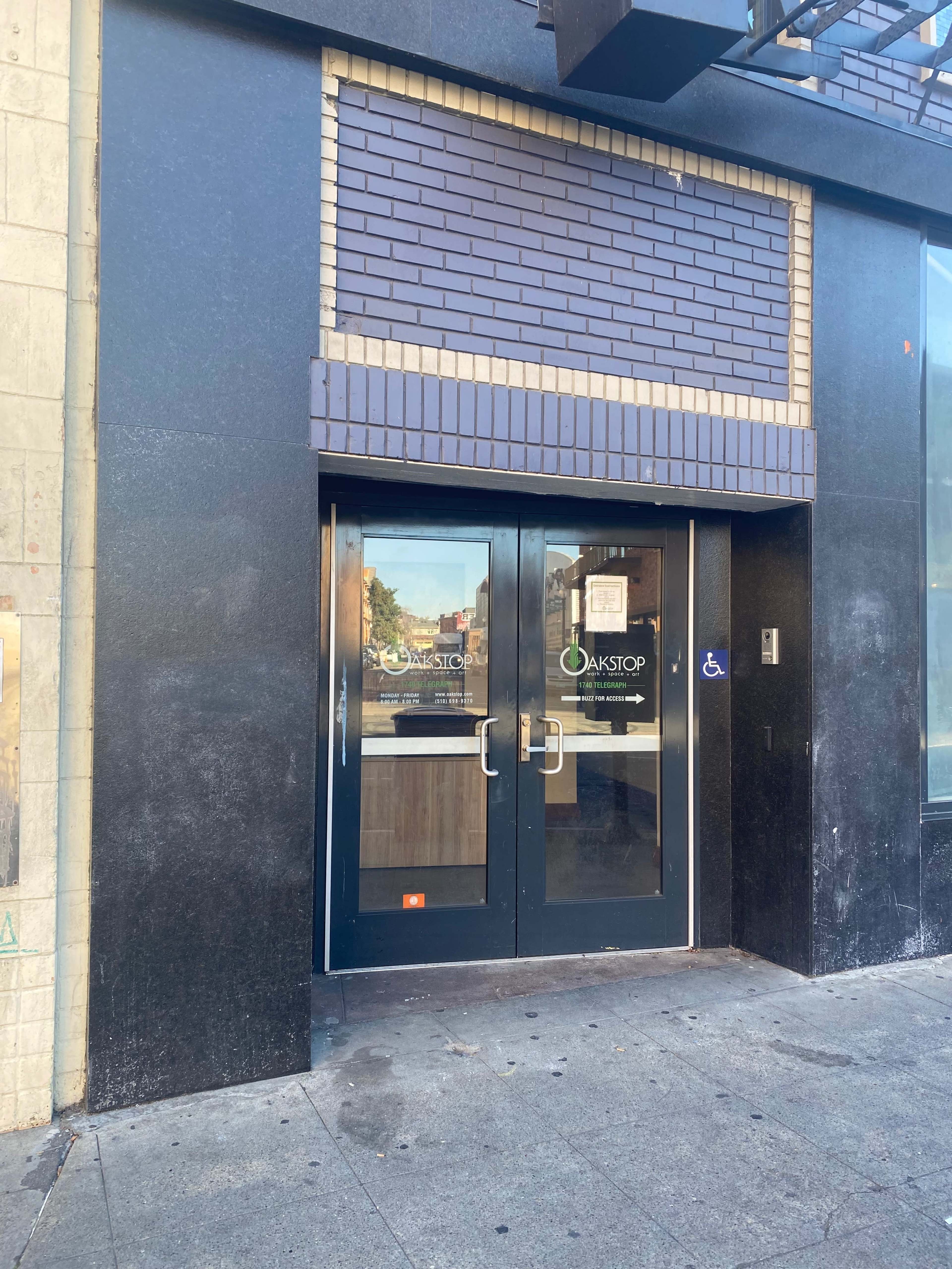 The image shows a set of double glass doors with a dark exterior wall and signage for "OAKSTOP" above them.