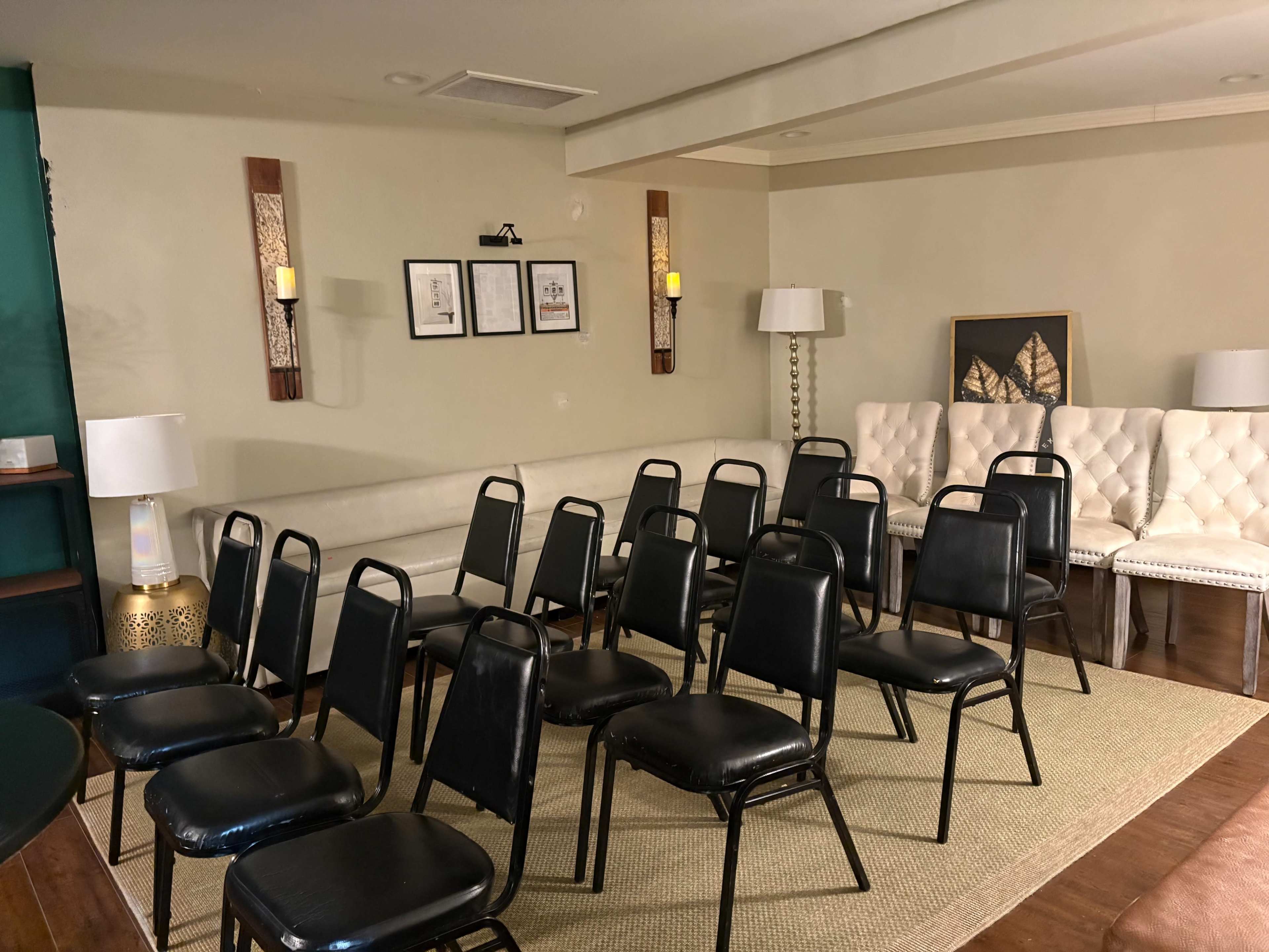 The image shows a room arranged with several black chairs facing a wall, with decorative lighting and furniture in the background.