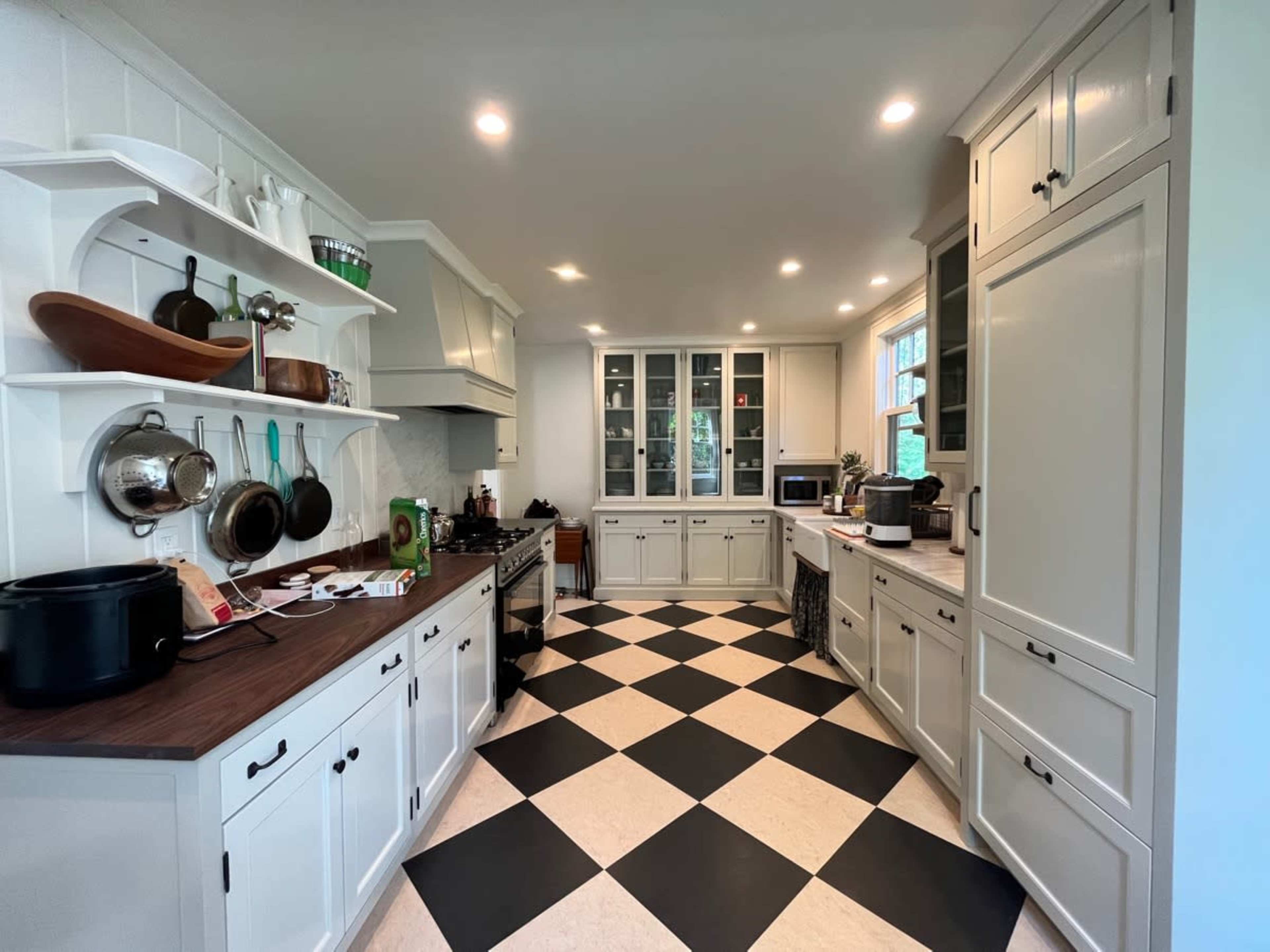 A kitchen with white cabinetry, a black and white checkered floor, and a mix of open shelving and closed cabinets.