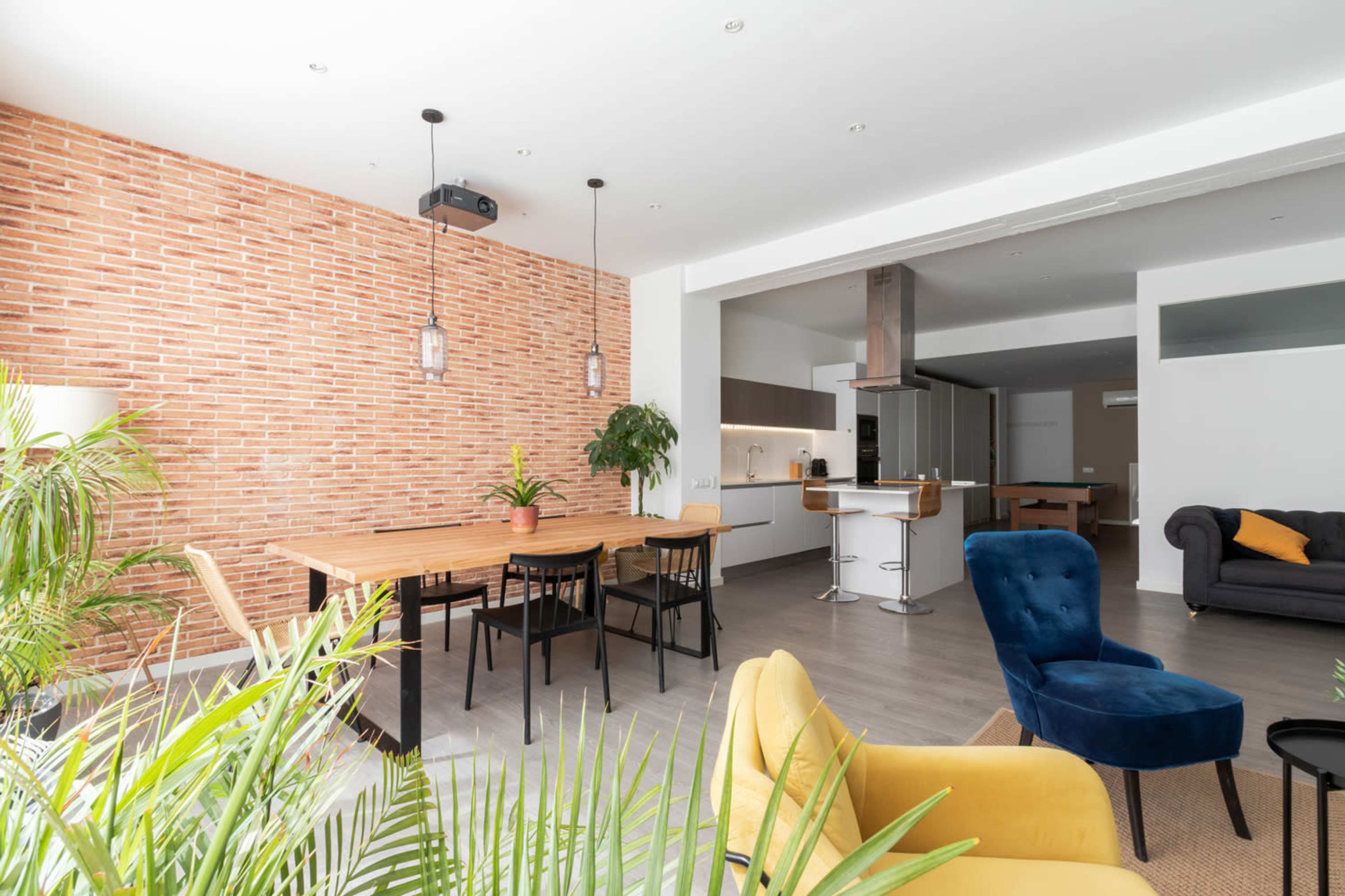 The image shows a modern interior space featuring a blend of brick and open-plan design, with a dining area, living area, and kitchen visible.