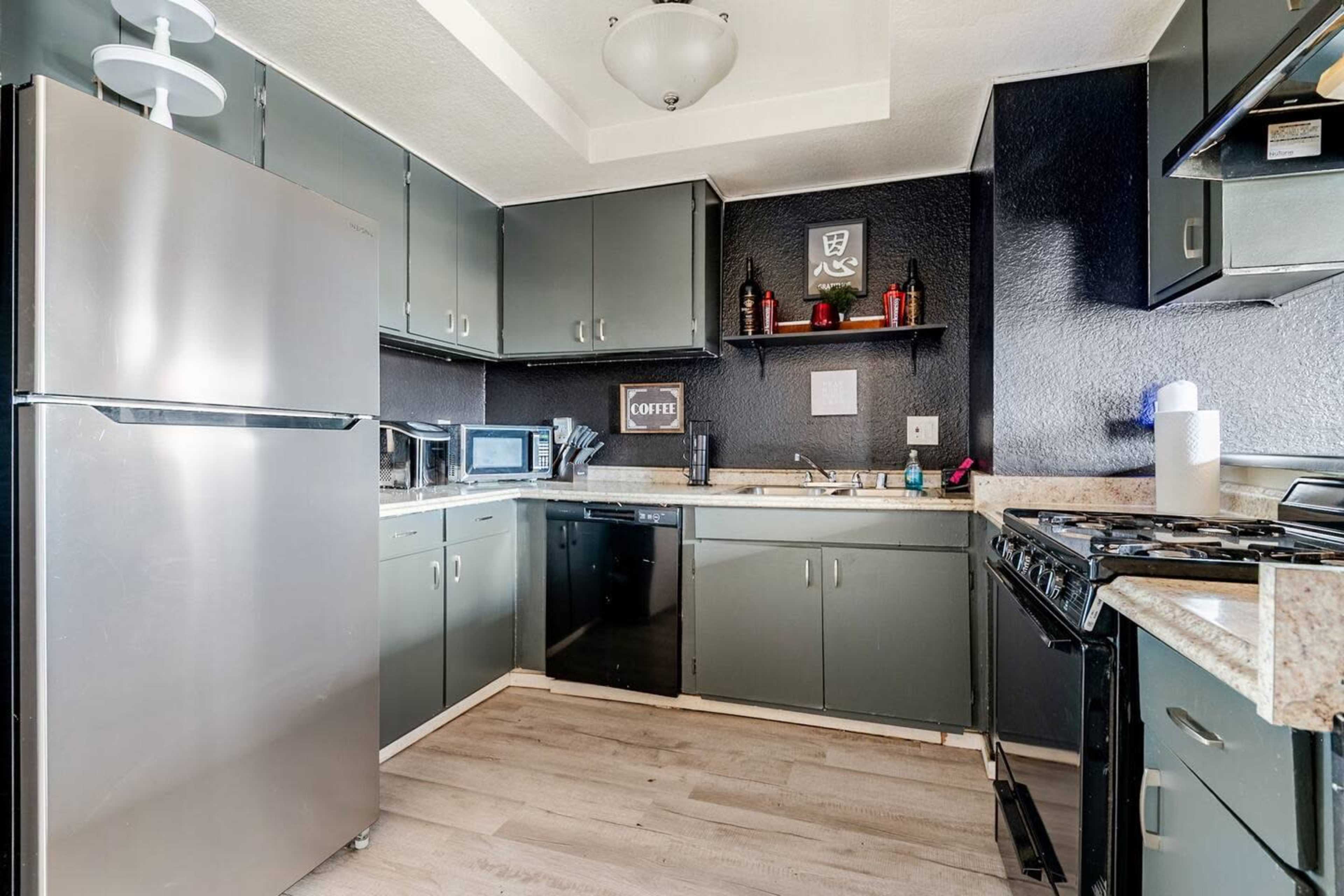 The image shows a modern kitchen with metallic appliances, dark cabinets, and a light-colored countertop.