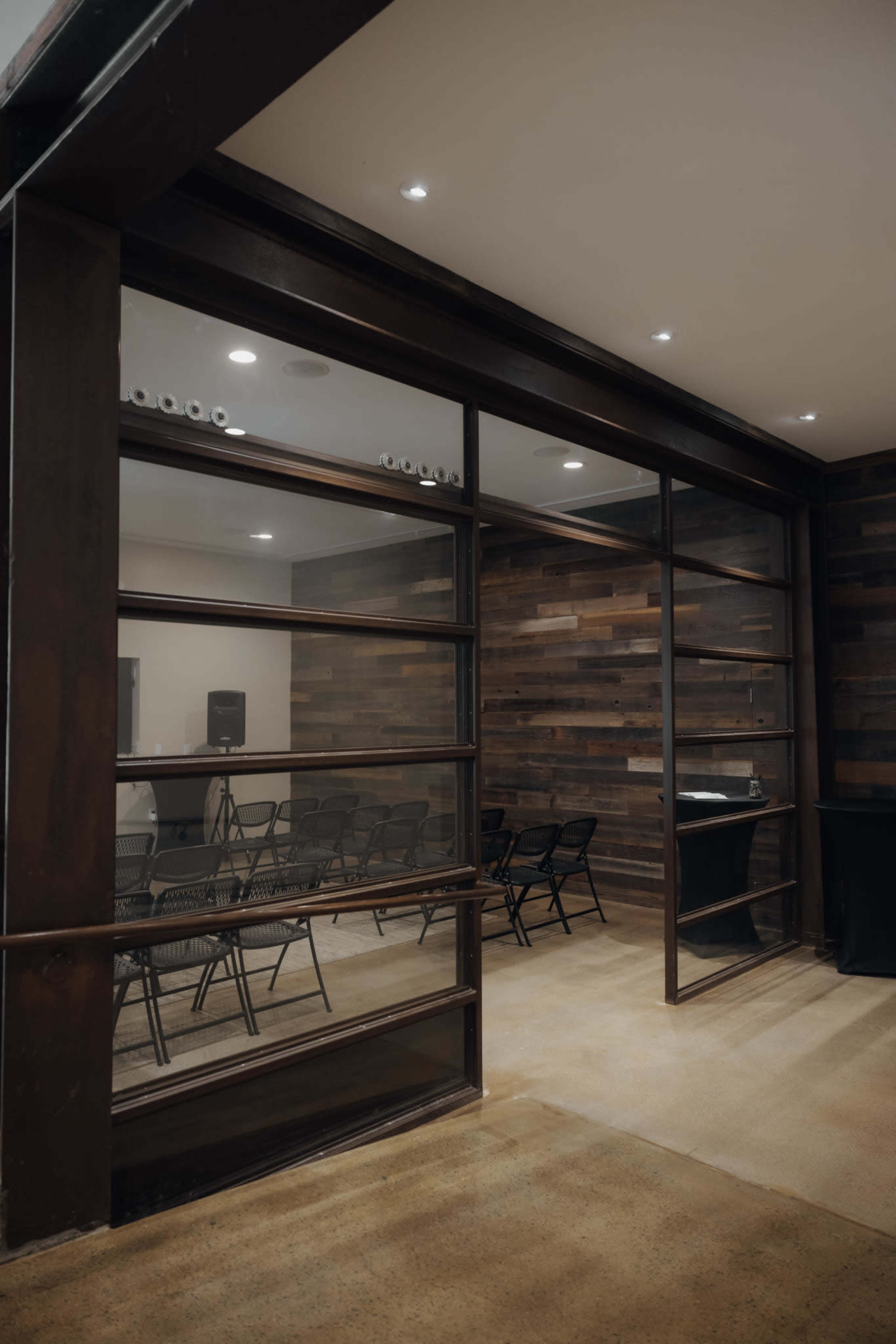 A room with glass walls containing several black chairs and a dark wooden interior.