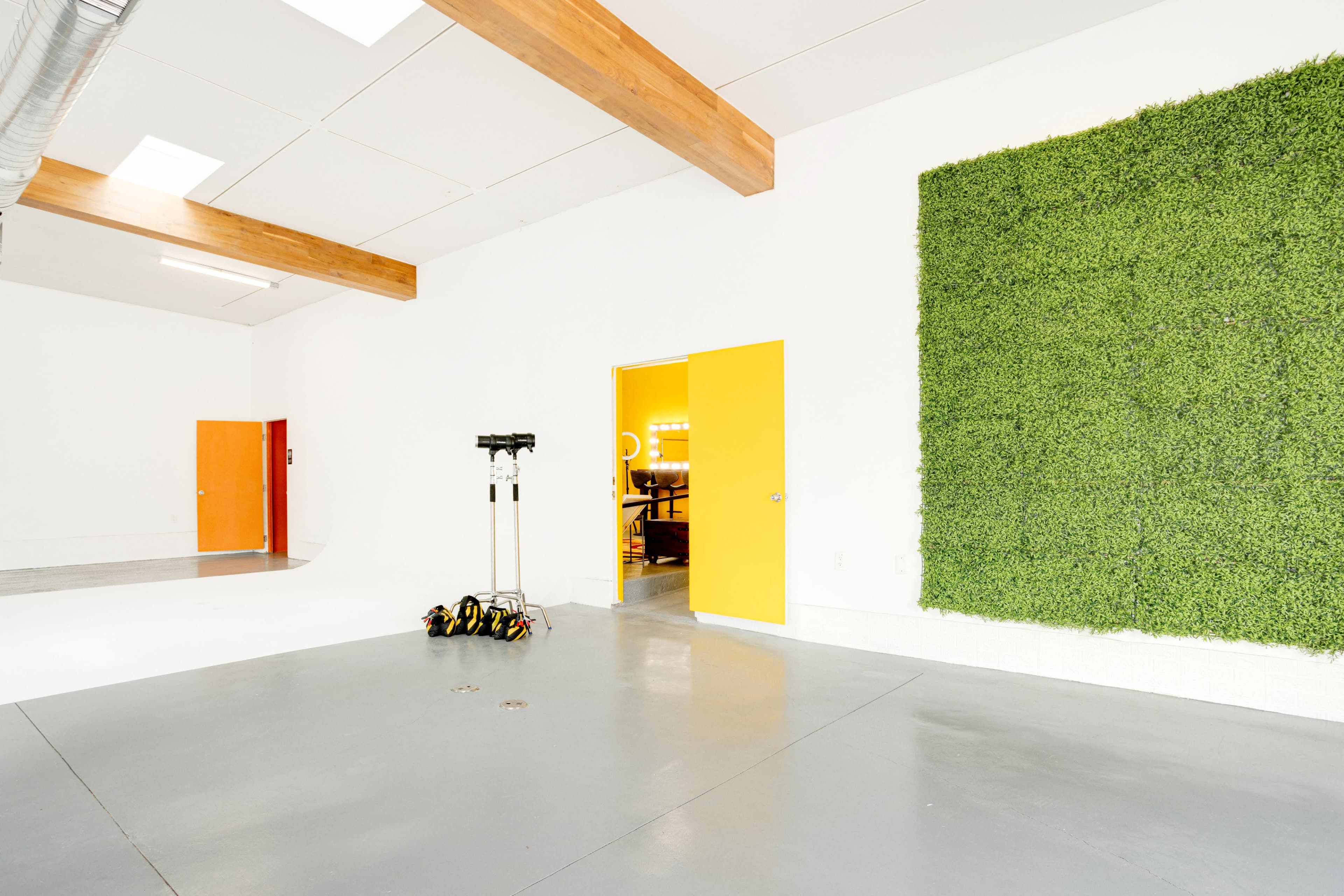 The image features a spacious, well-lit room with a green living wall on one side and a bright yellow door leading to another area.