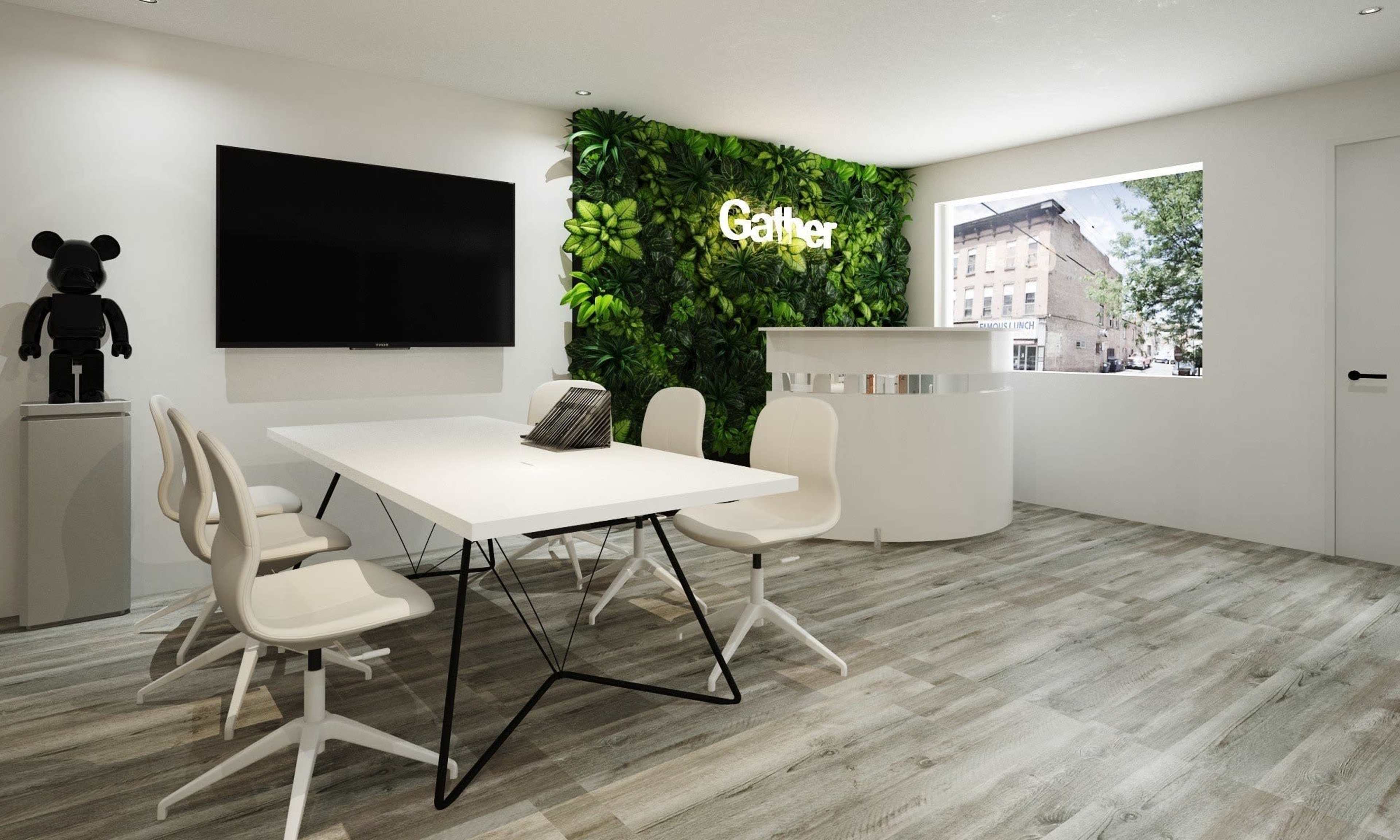 A modern conference room featuring a white table with chairs, a green plant wall, a television, and a reception area.