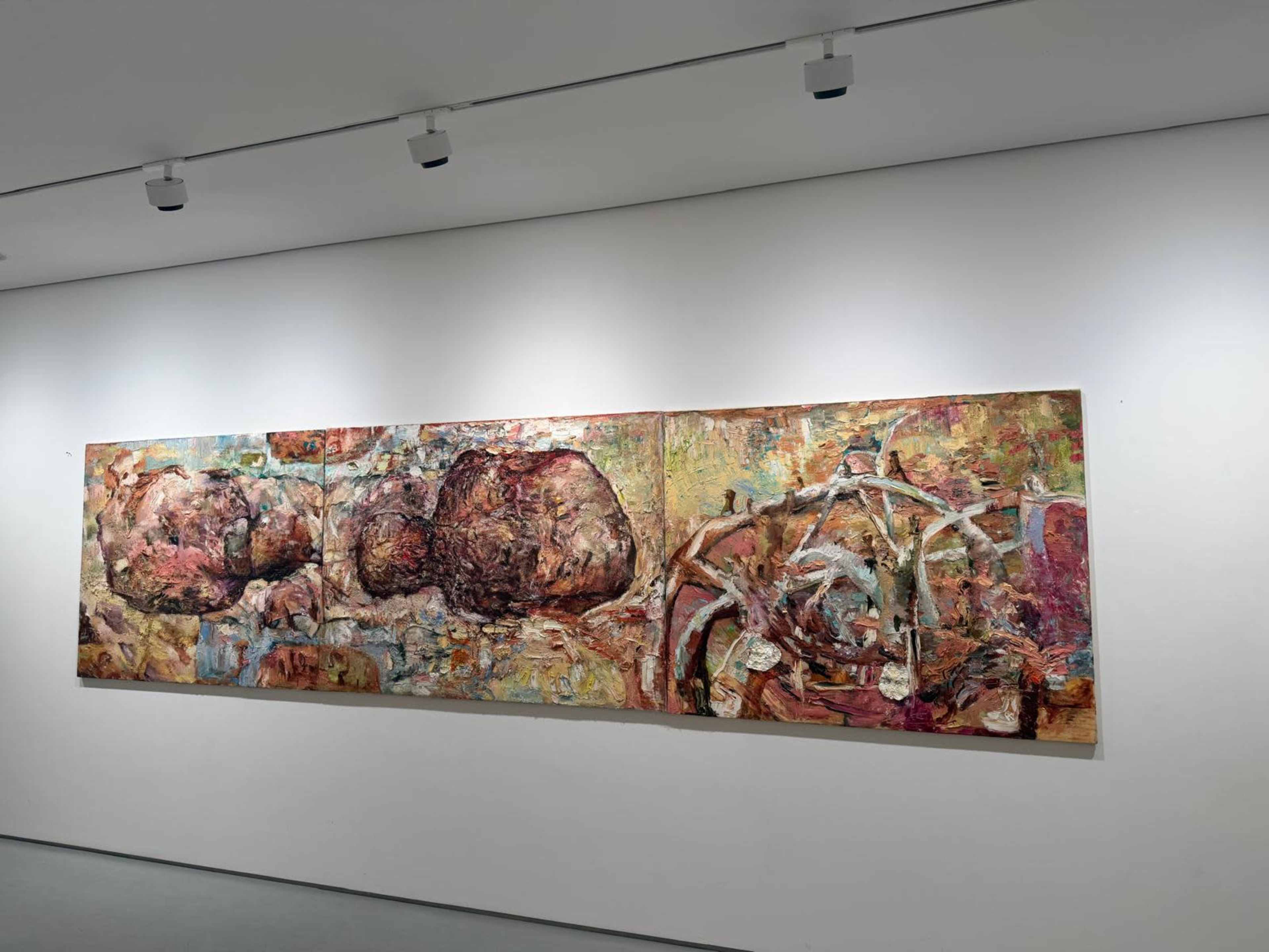 The image shows a large abstract mural displayed on a white wall, featuring textured forms and a variety of colors.