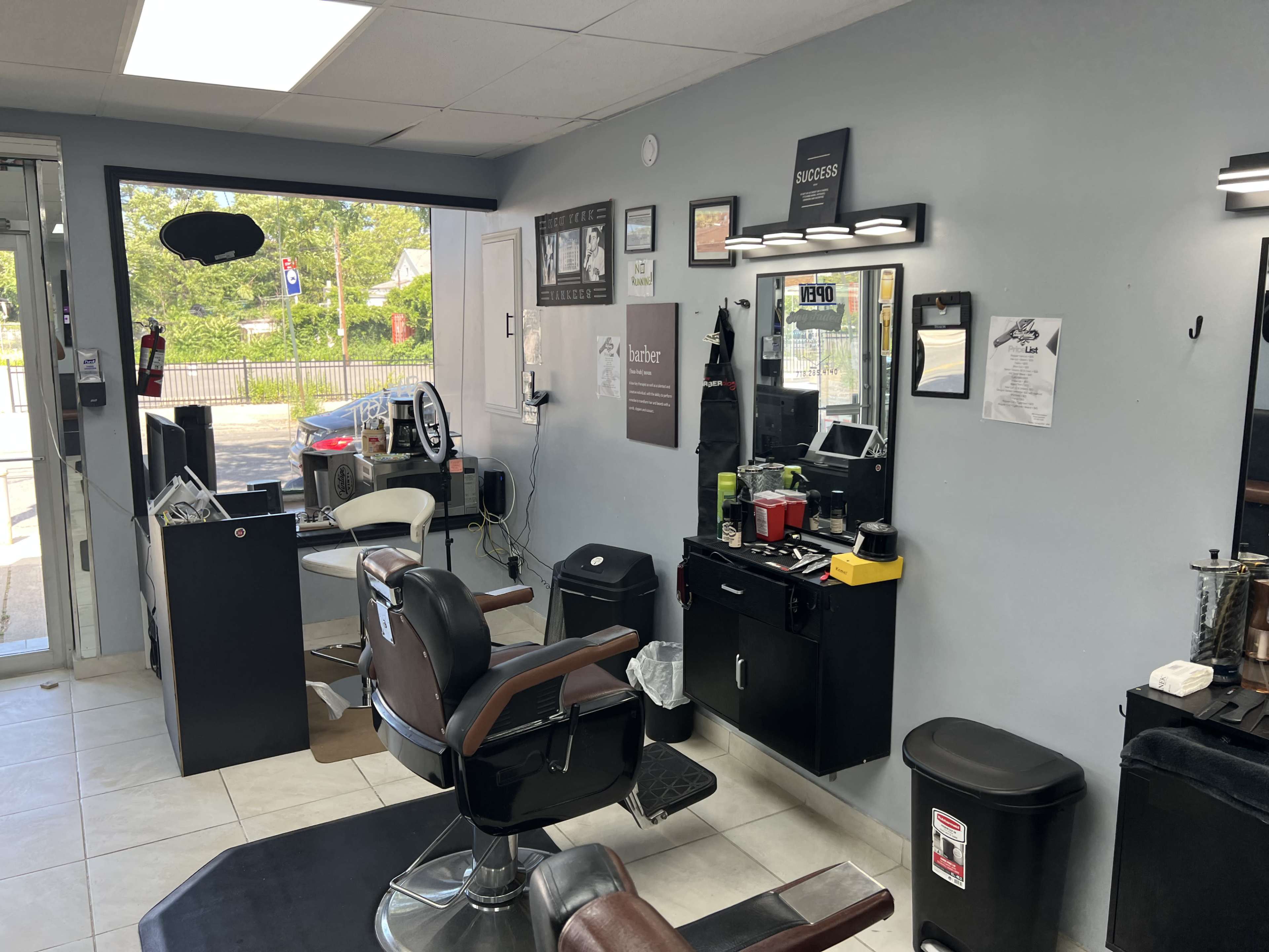 The image shows the interior of a barbershop with a barber chair, a mirror, and various styling tools displayed on a counter.