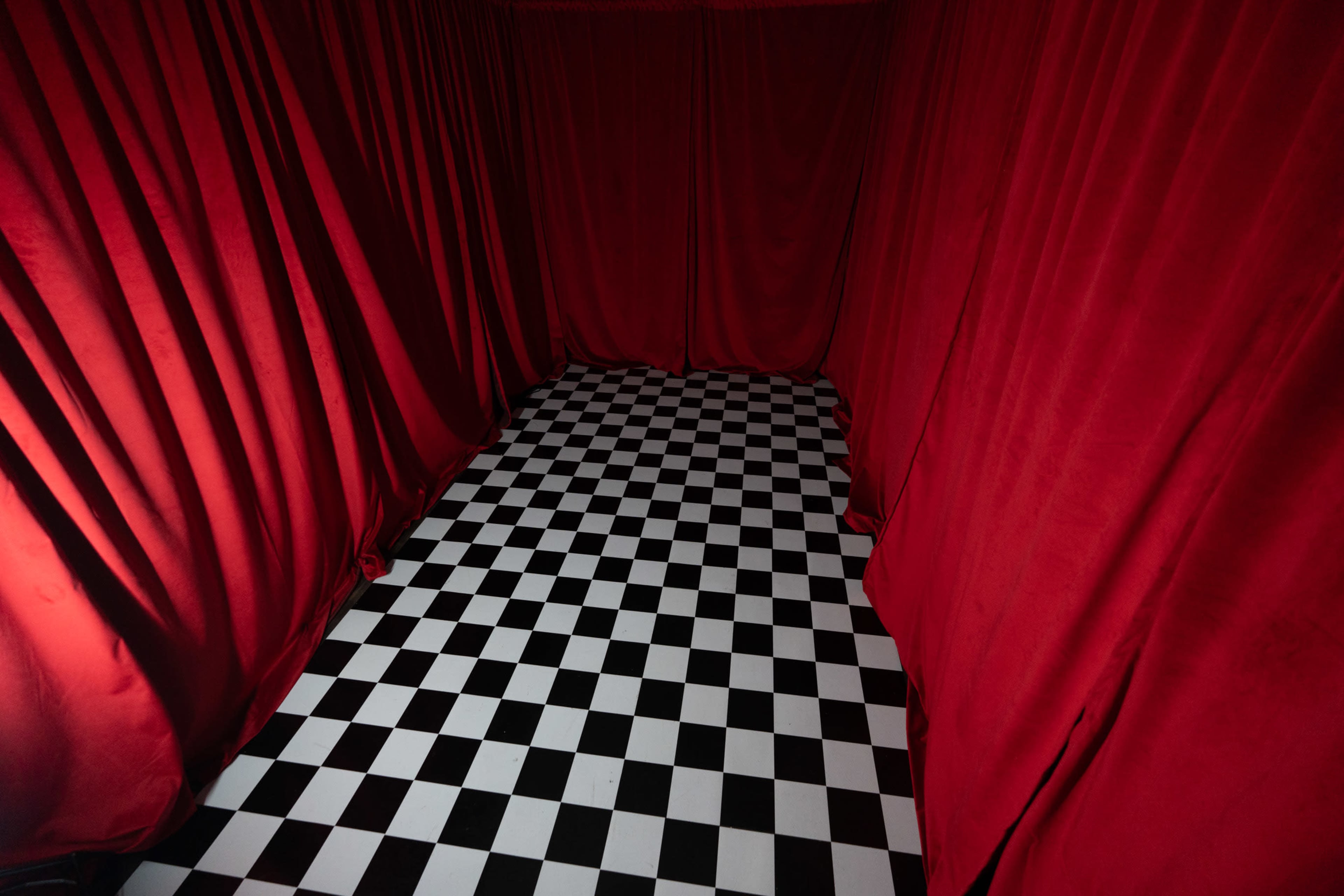 A small room with red curtains and a black-and-white checkered floor.