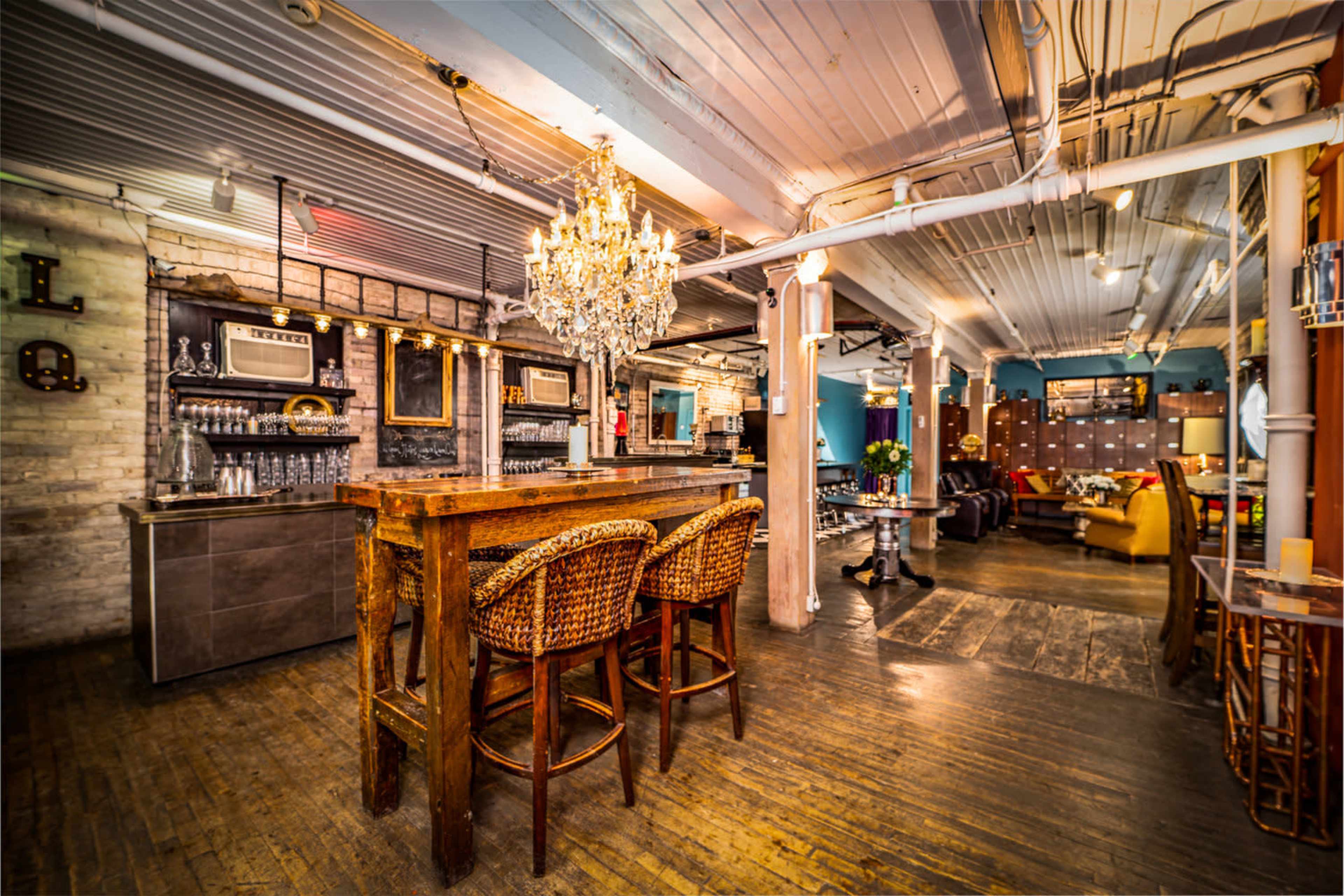 A spacious, well-lit bar area with wooden furniture, a chandelier, and various seating arrangements.