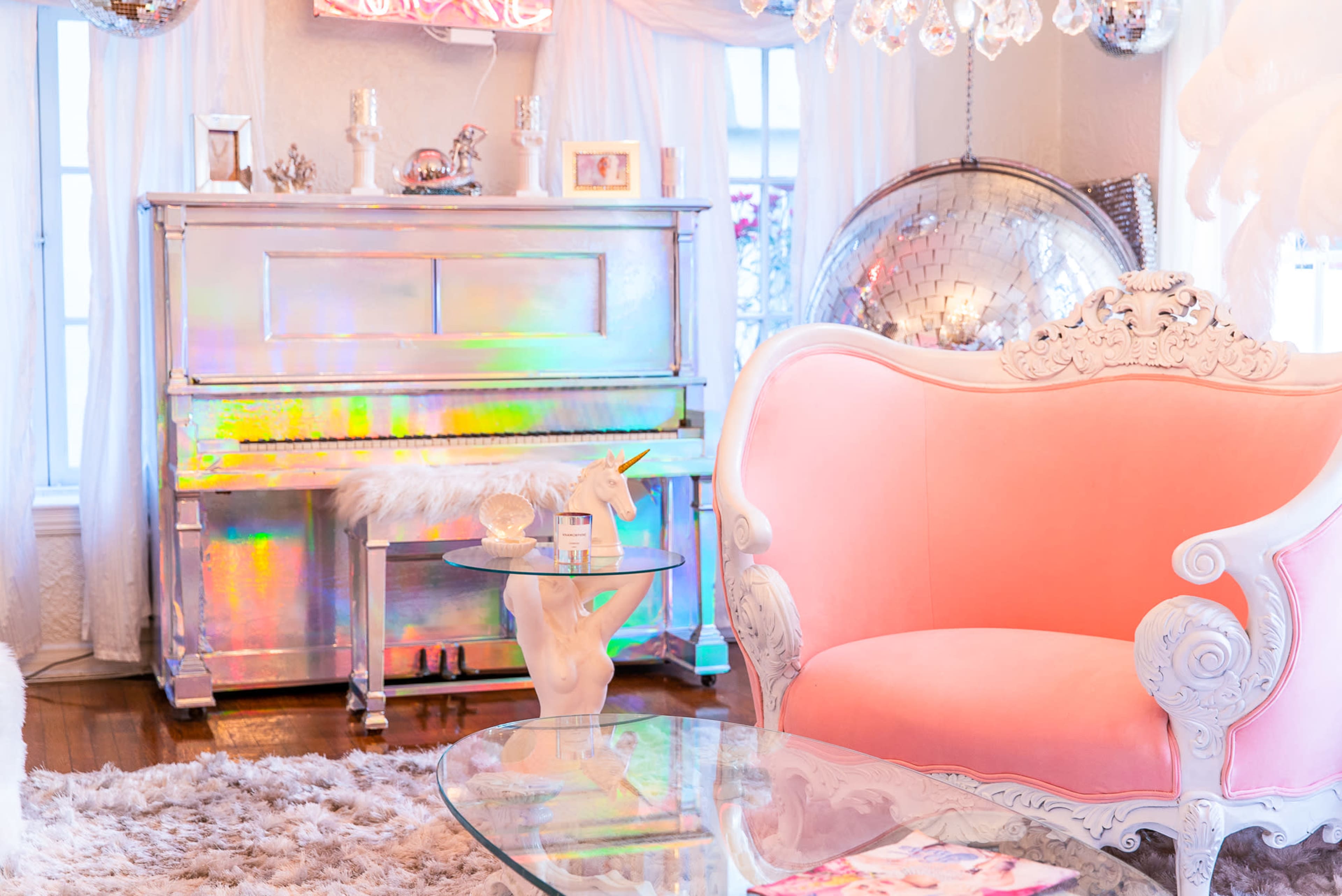 The scene features a brightly colored room with a silver piano, a pink ornate chair, and a small table held by a unicorn base.