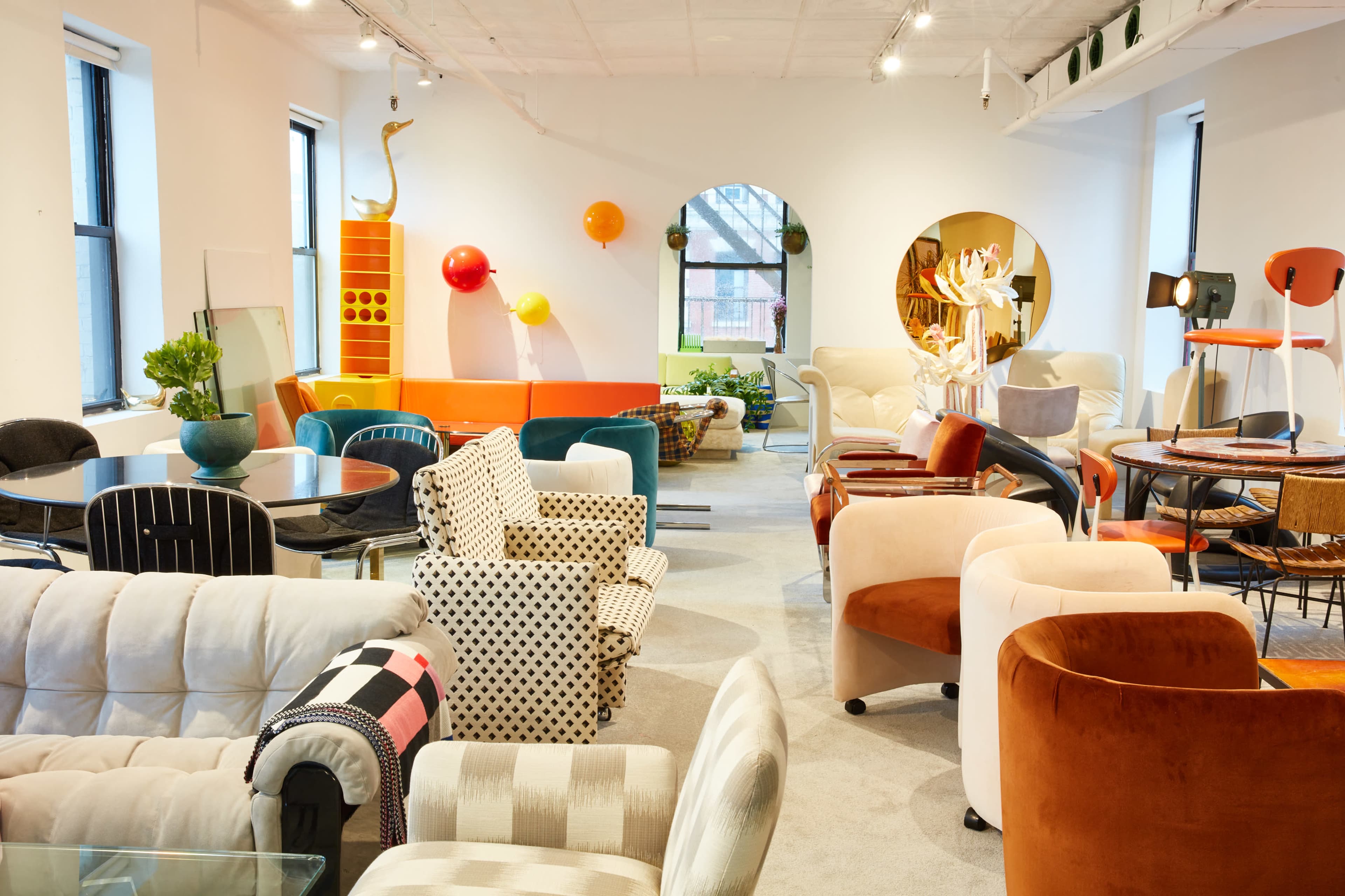 The scene features a brightly lit furniture showroom filled with a variety of colorful chairs, sofas, and decorative elements.