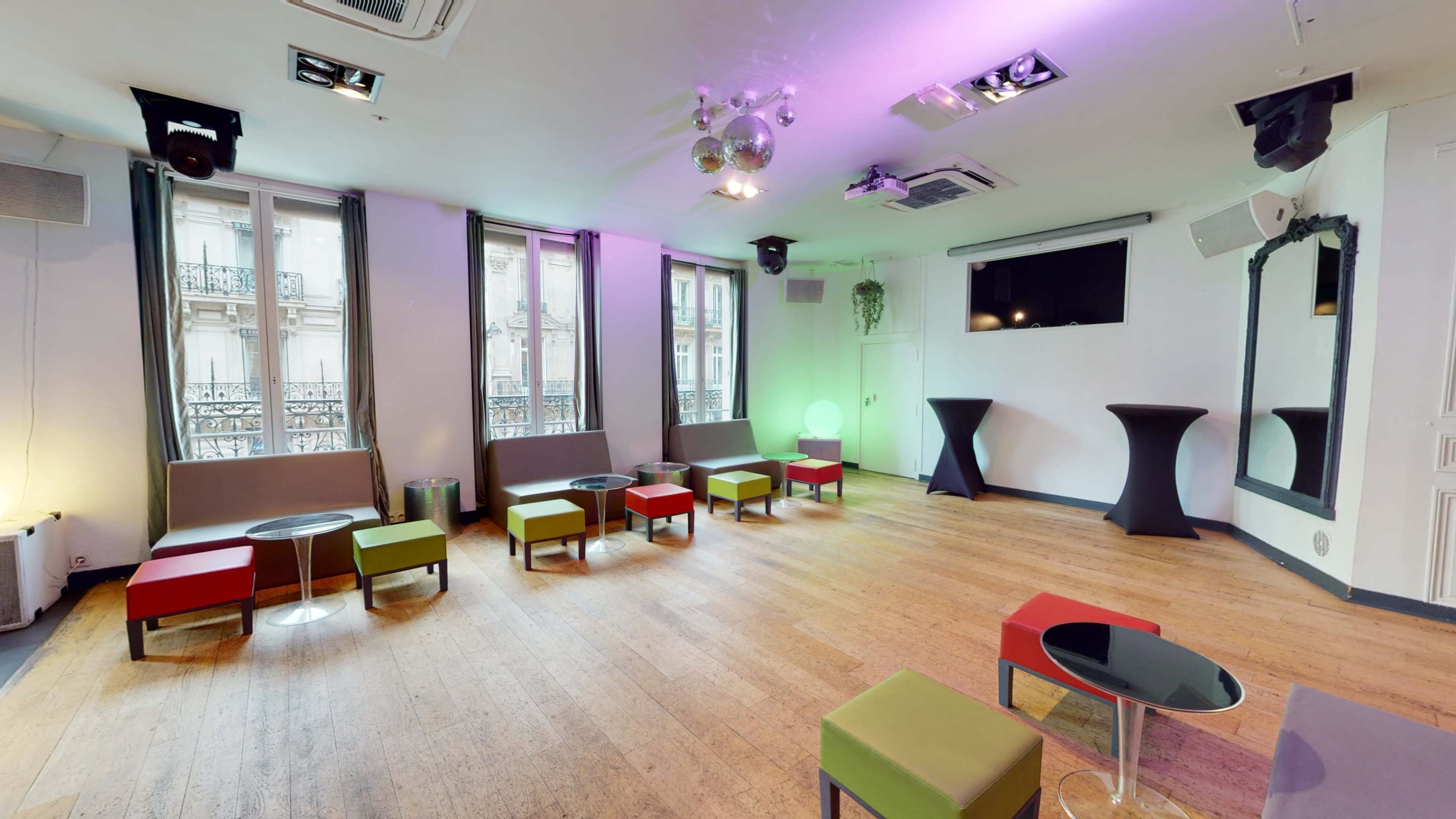 A modern events space with colorful seating, wooden floors, and large windows providing natural light.