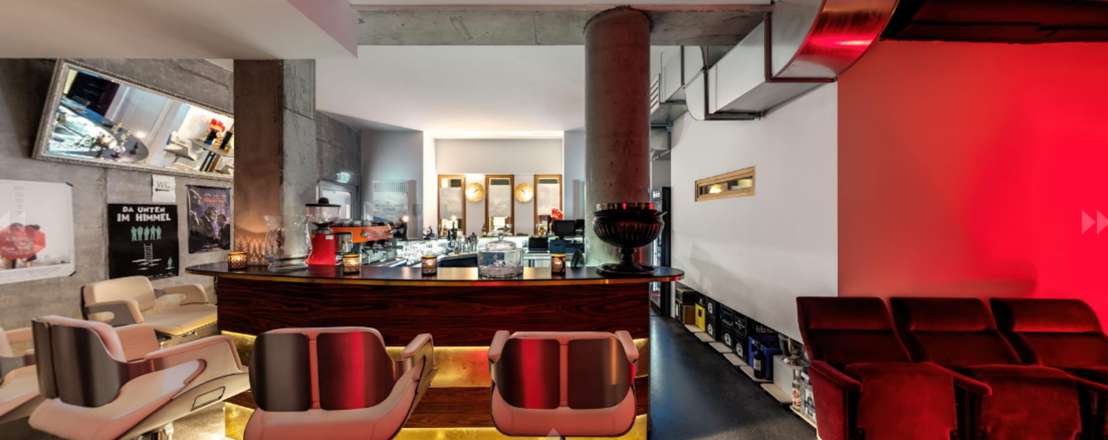 A modern bar area with a wooden counter, comfortable seating, and ambient lighting.