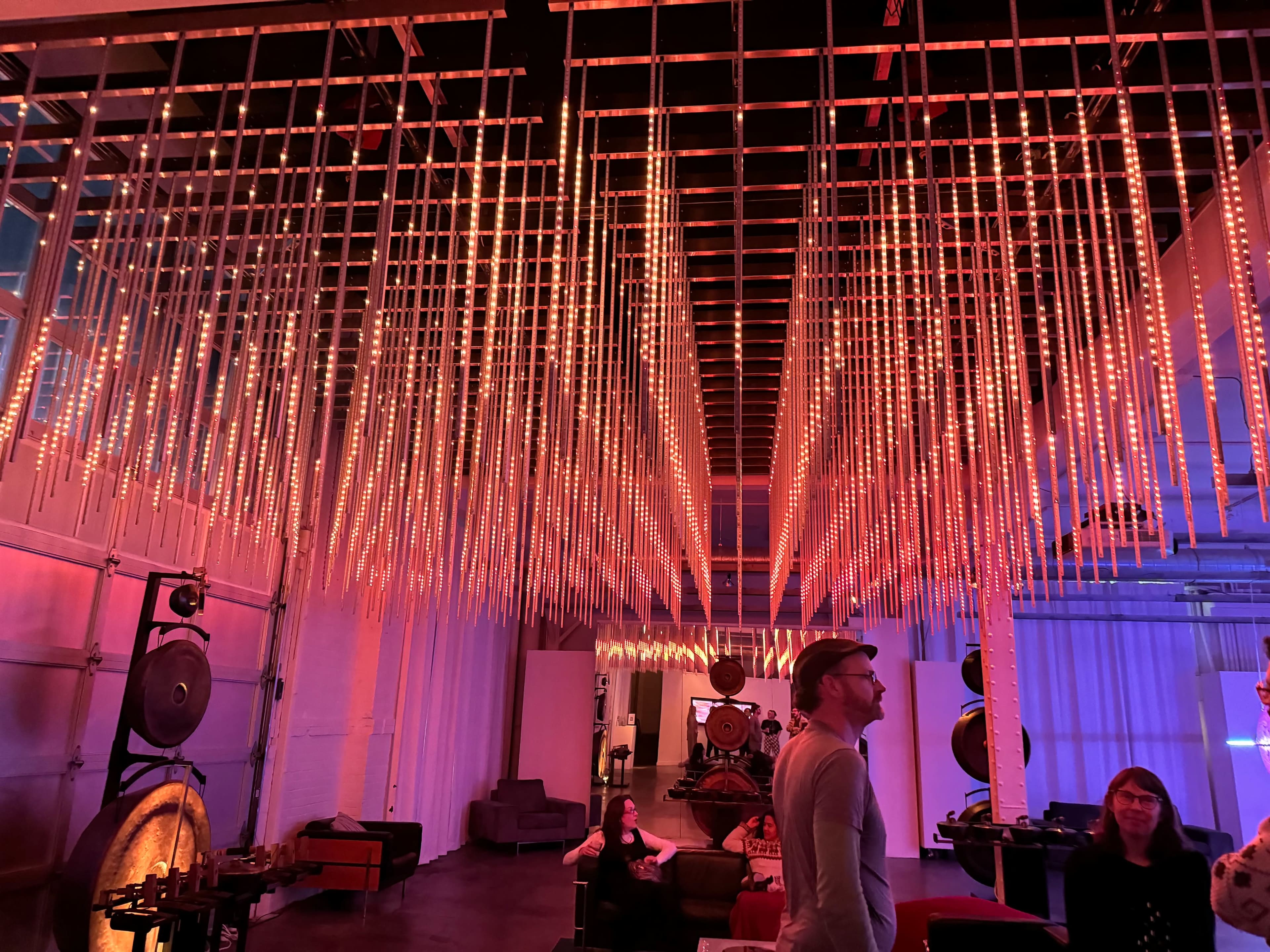 The image shows a modern interior space with LED lights hanging from the ceiling, creating a striking visual display above a seating area.