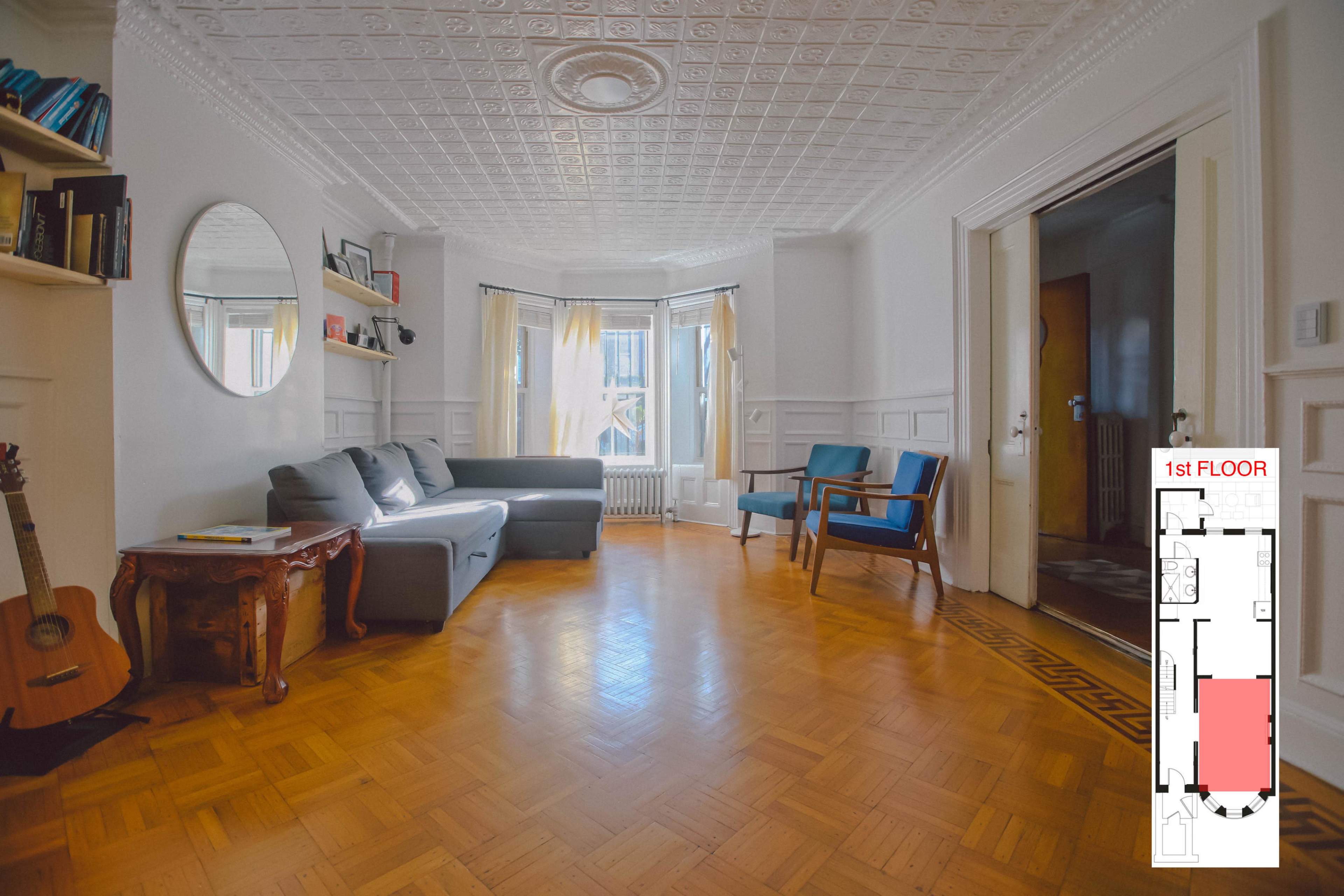 A spacious living room with a gray sofa, wooden furniture, and a decorative ceiling.