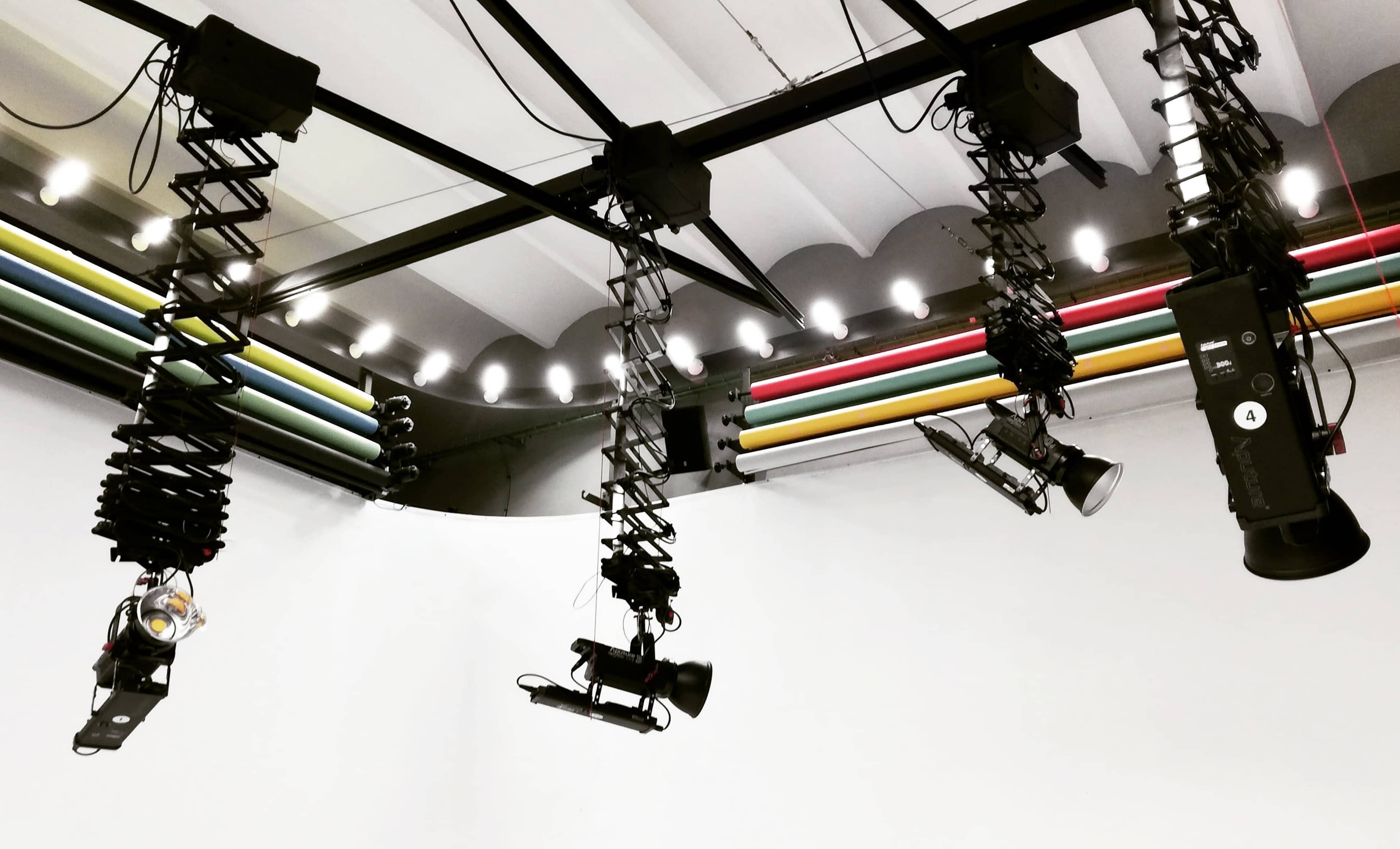 A studio ceiling with suspended lighting rigs and colorful cables.