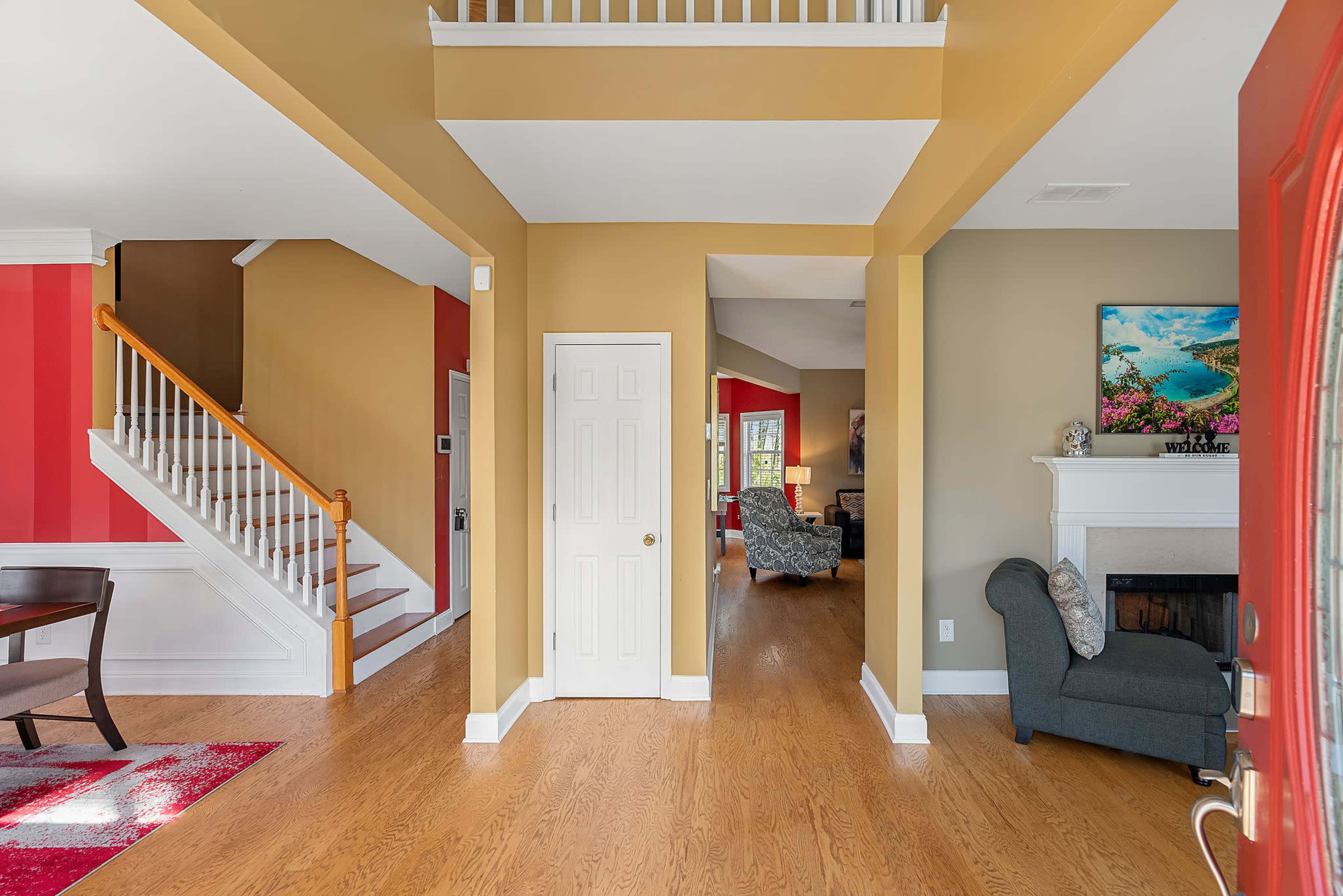 An interior entryway leading to a staircase, with a view into a living area featuring a fireplace and furniture.