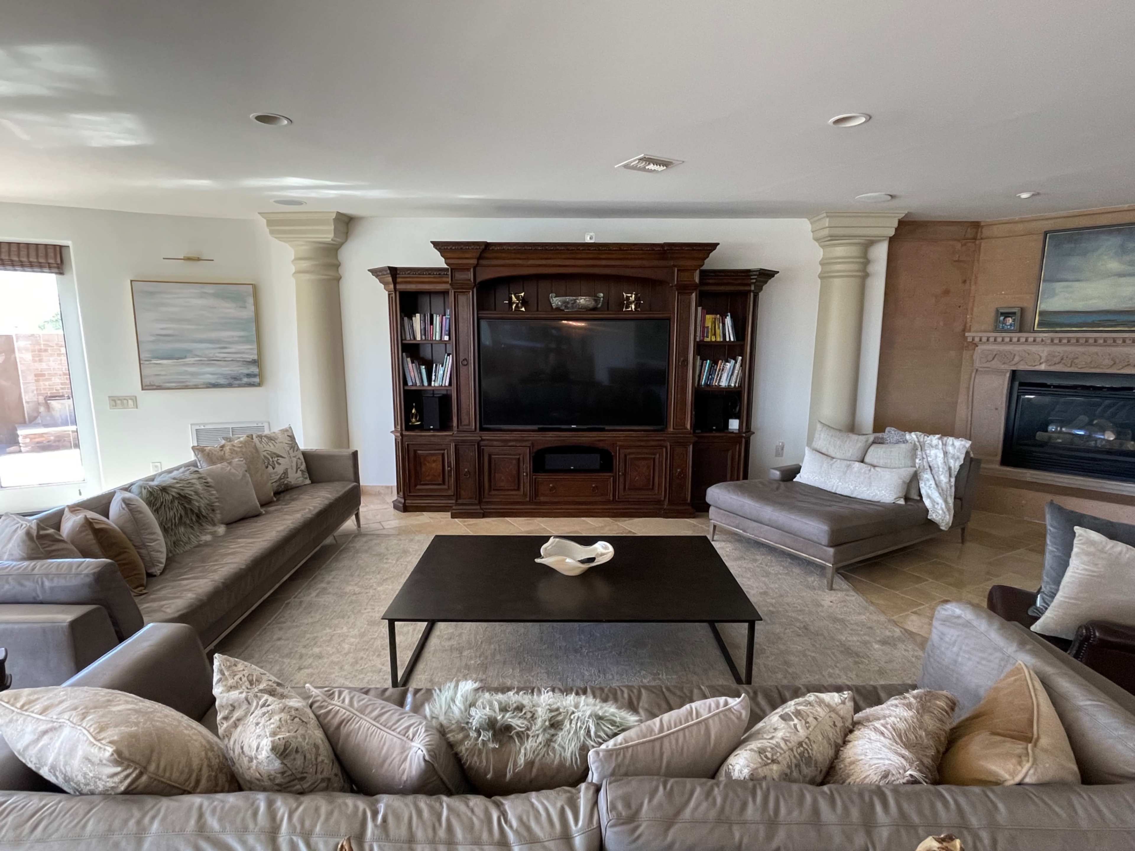 The living room features two sofas facing a central coffee table, with an entertainment unit and a fireplace against the wall.