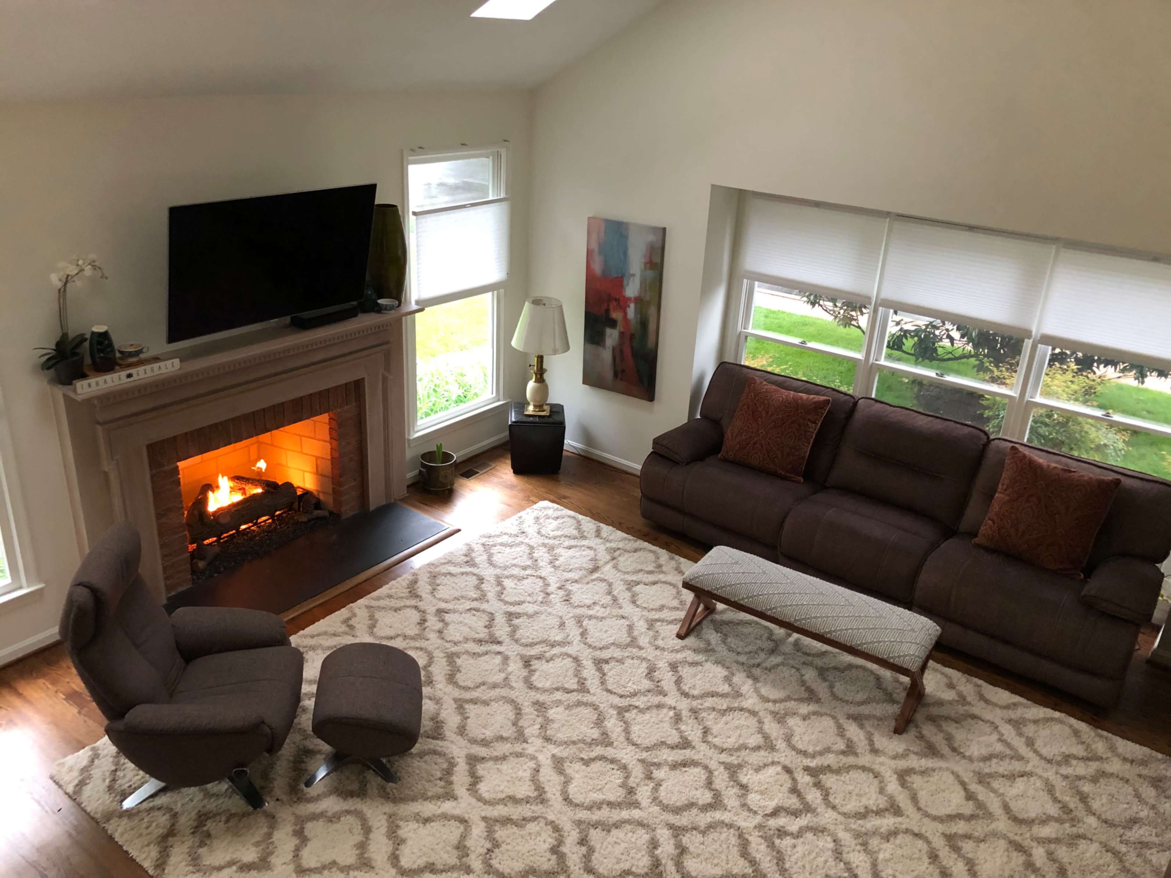 The image shows a living room with a fireplace, two sofas, a coffee table, and a television mounted on the wall.