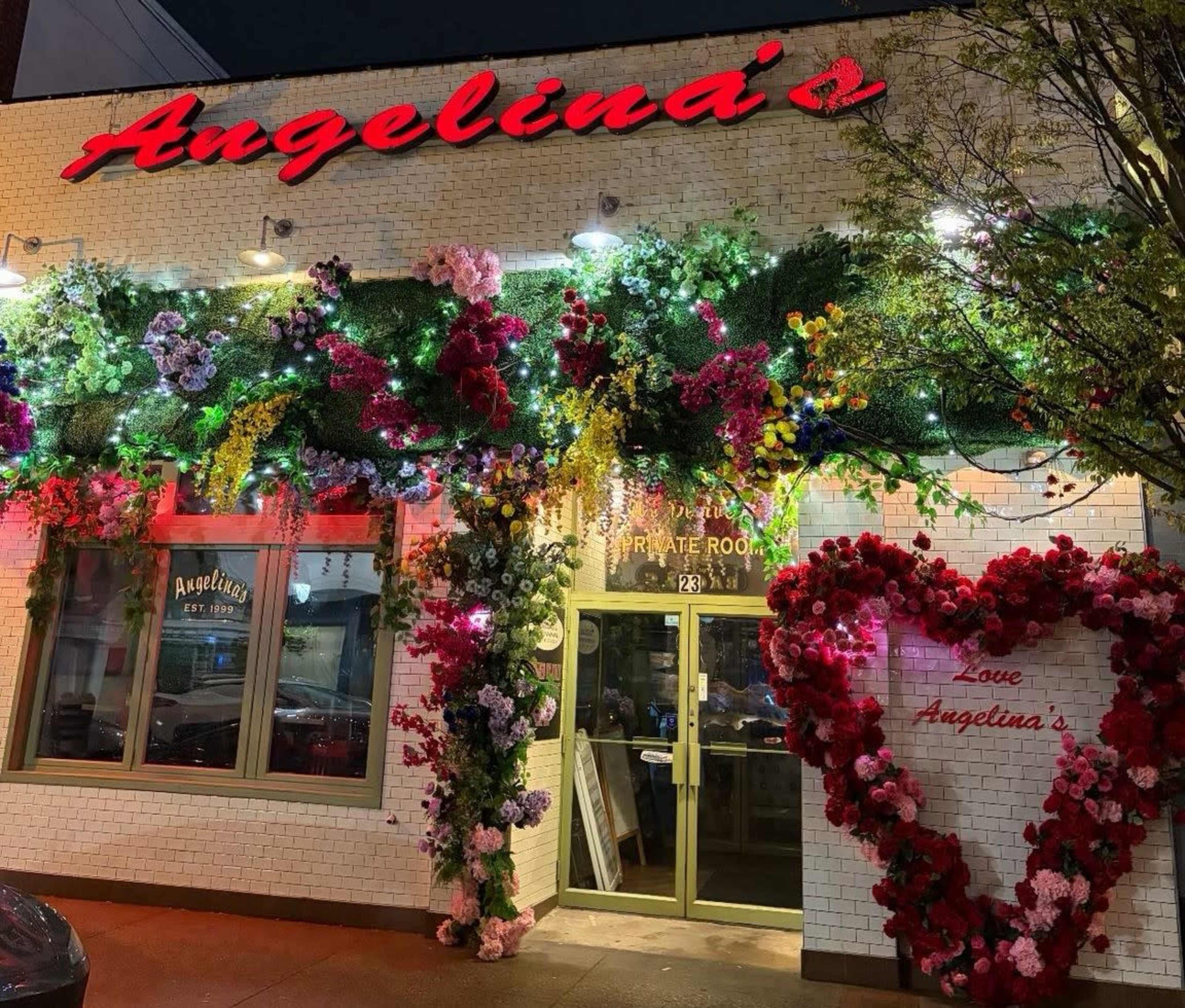 The exterior of Angelina's restaurant features vibrant floral decorations and illuminated signage.
